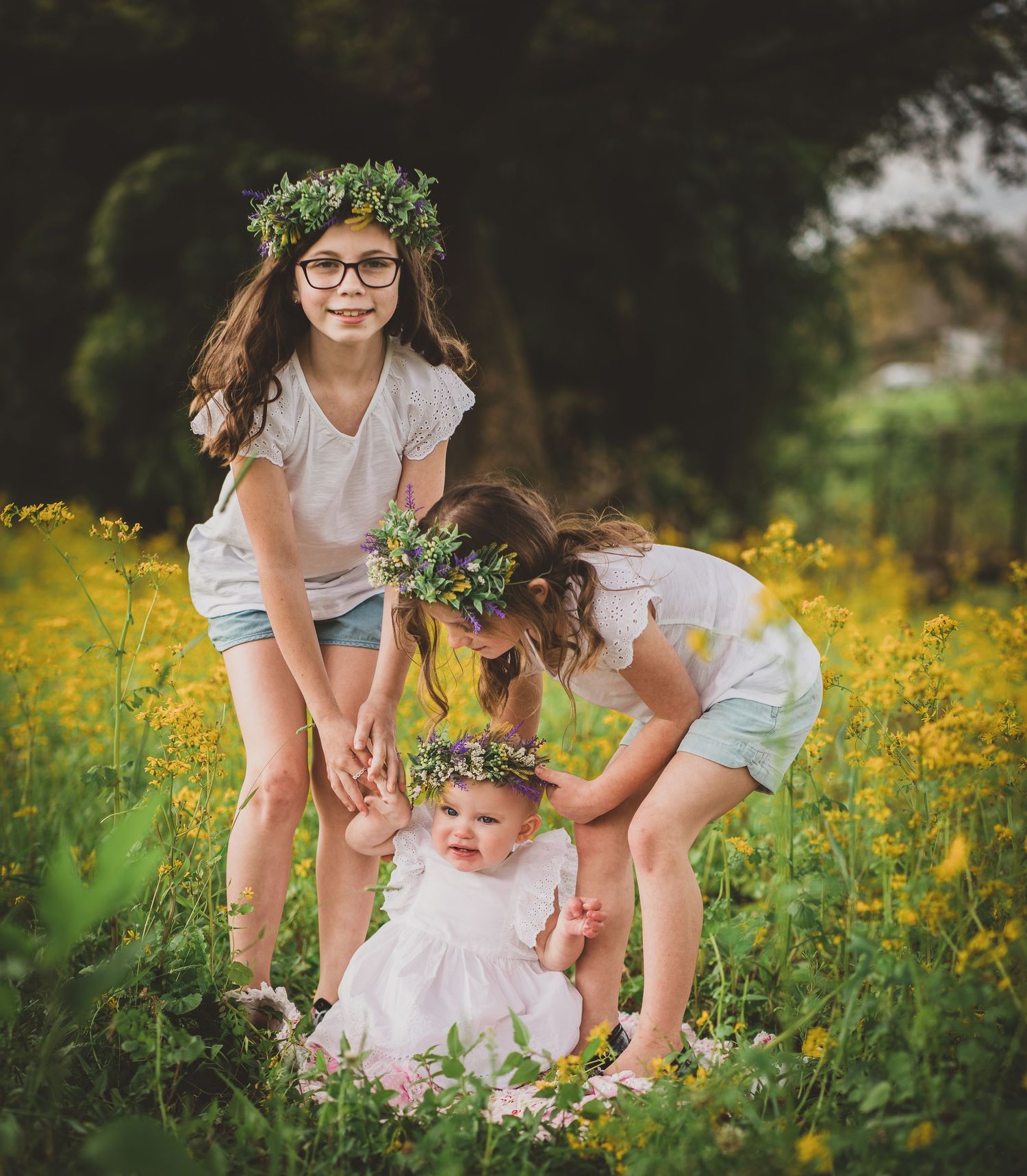 Candid moment of siblings with floral crowns playing together in a yellow wildflower field.