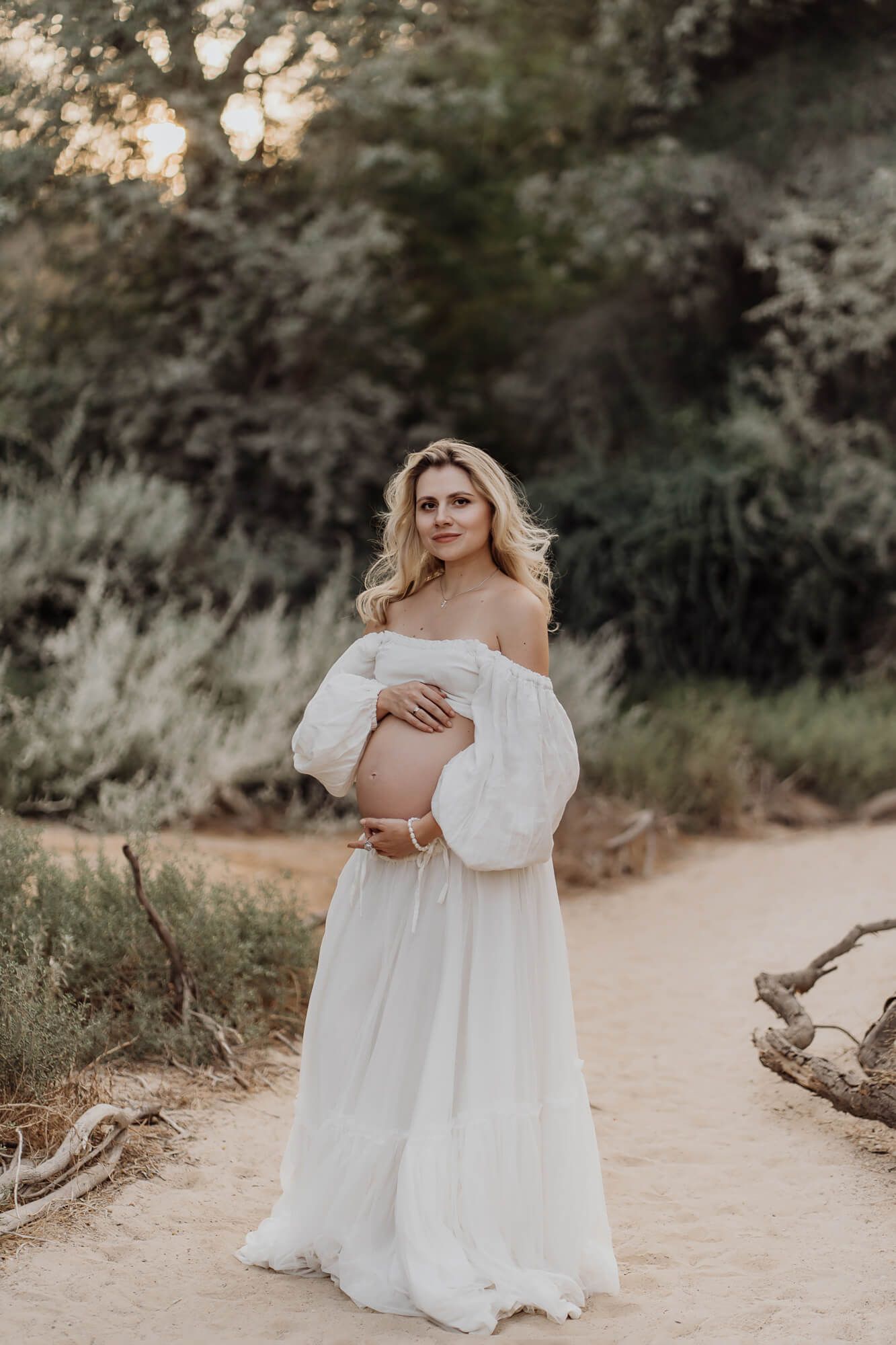A dreamy maternity photograph captured on a winding dirt path surrounded by greenery.