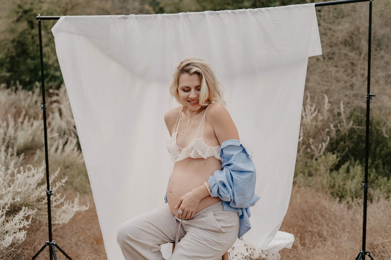 Artistic maternity portrait outdoors with white backdrop and denim accents.