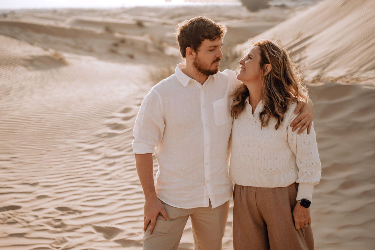 Candid desert photoshoot with warm lighting and natural expressions against sandy terrain.