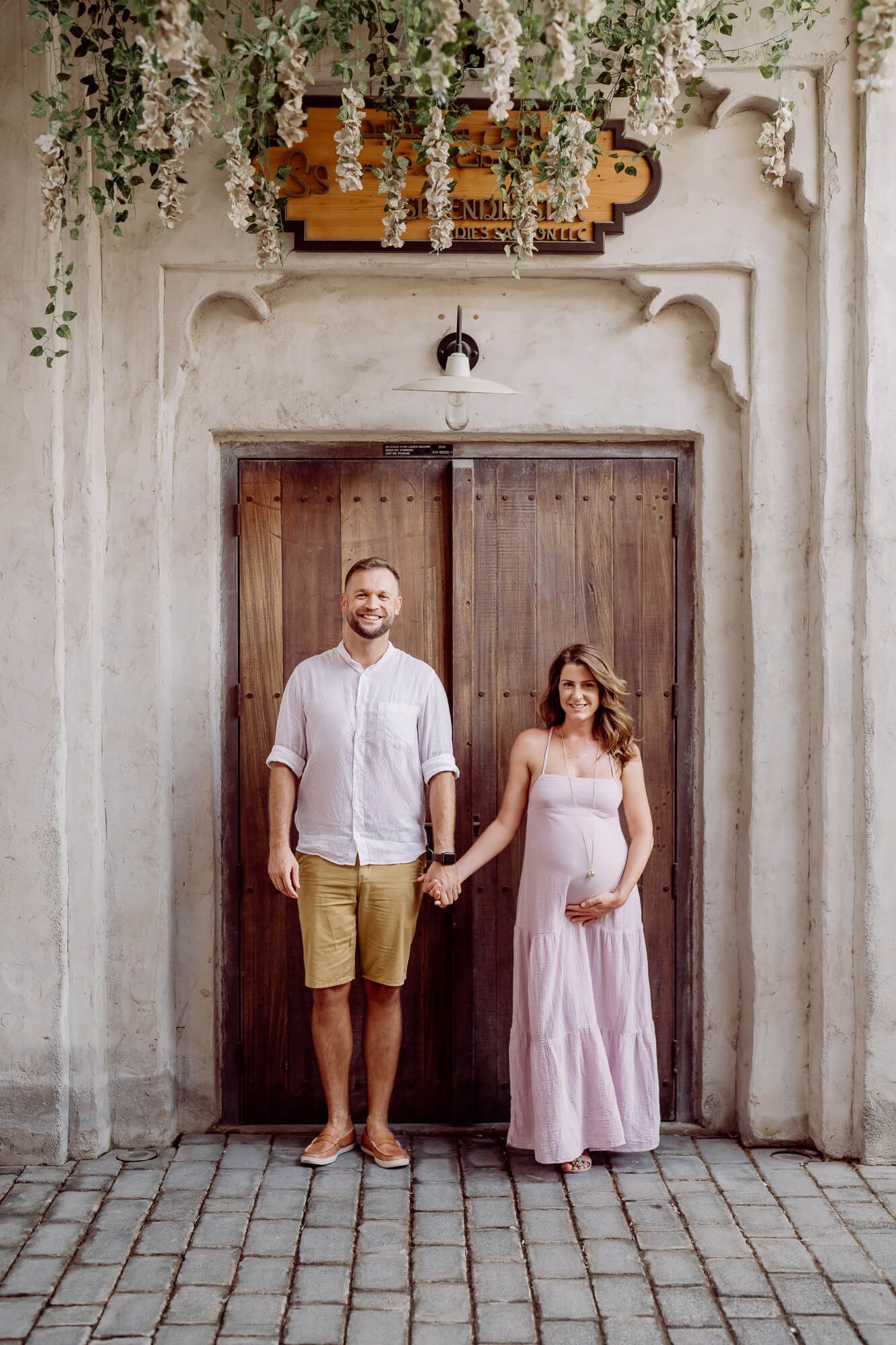 Romantic collage series showing couple posing against rustic white walls and wooden doors in matching light outfits.