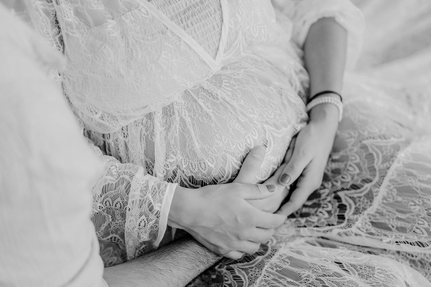 A delicate close-up detail of white lace and tulle fabric with intricate floral patterns and beading textures.