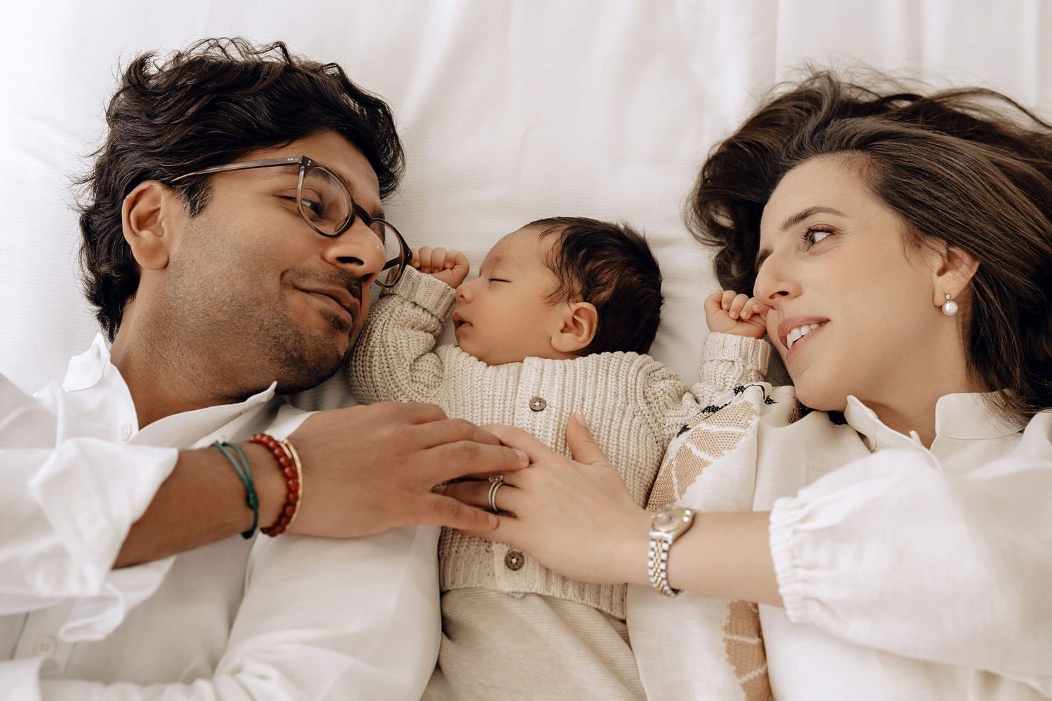 Candid family photography session showing loving interactions on white bedding.
