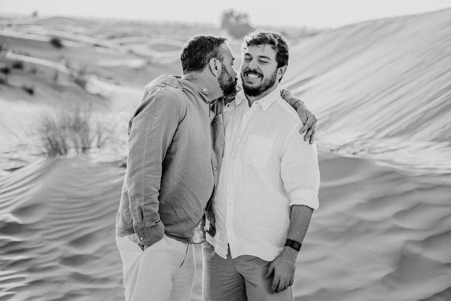 Desert landscape photo with two people laughing together in casual attire.