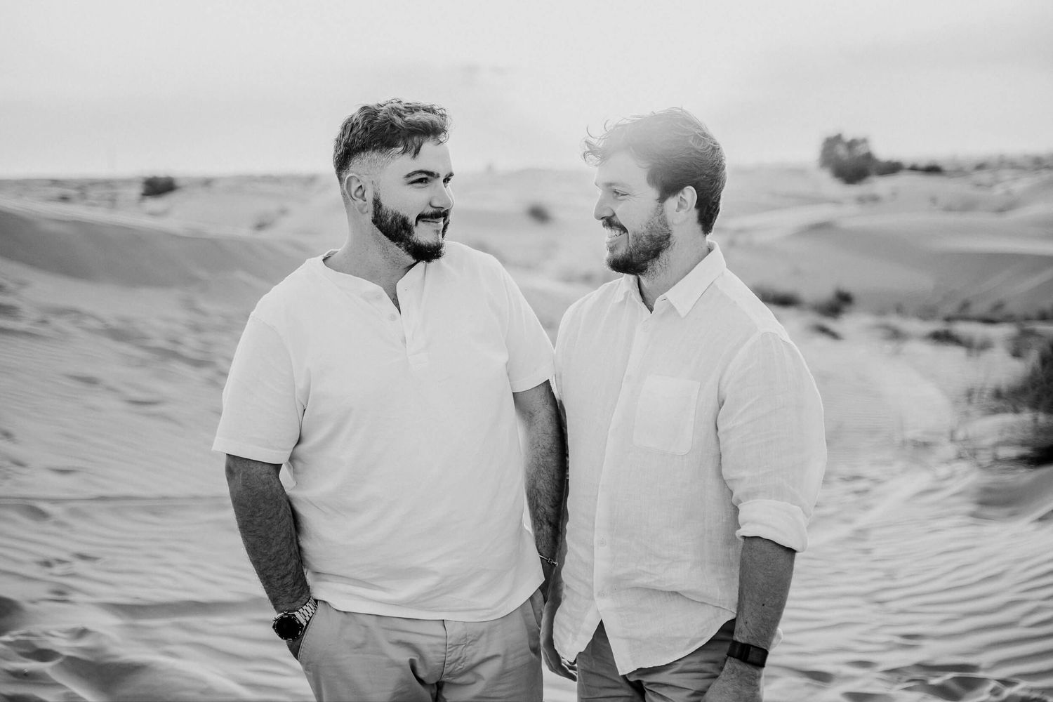 Black and white portrait of two people in white shirts conversing in desert setting.