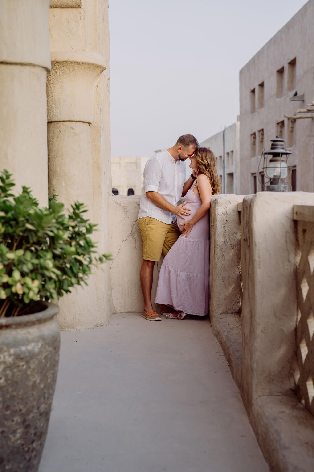 Intimate maternity moment captured between columns and architecture in warm evening light.