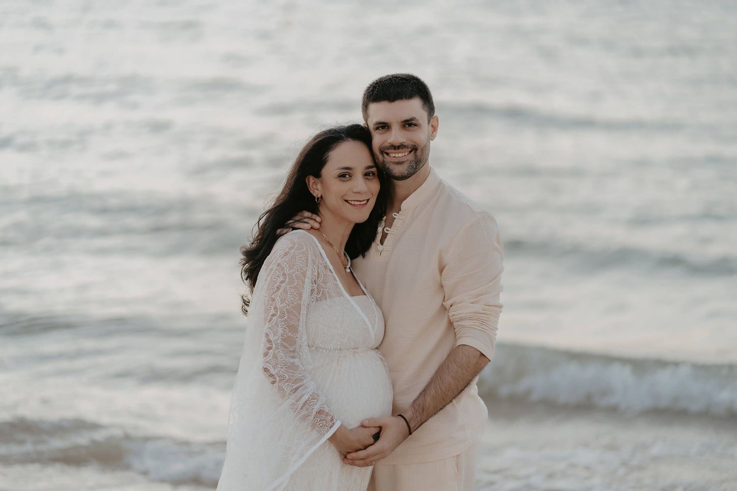 A couple embraces on a misty beach in soft muted tones during a romantic photoshoot session.