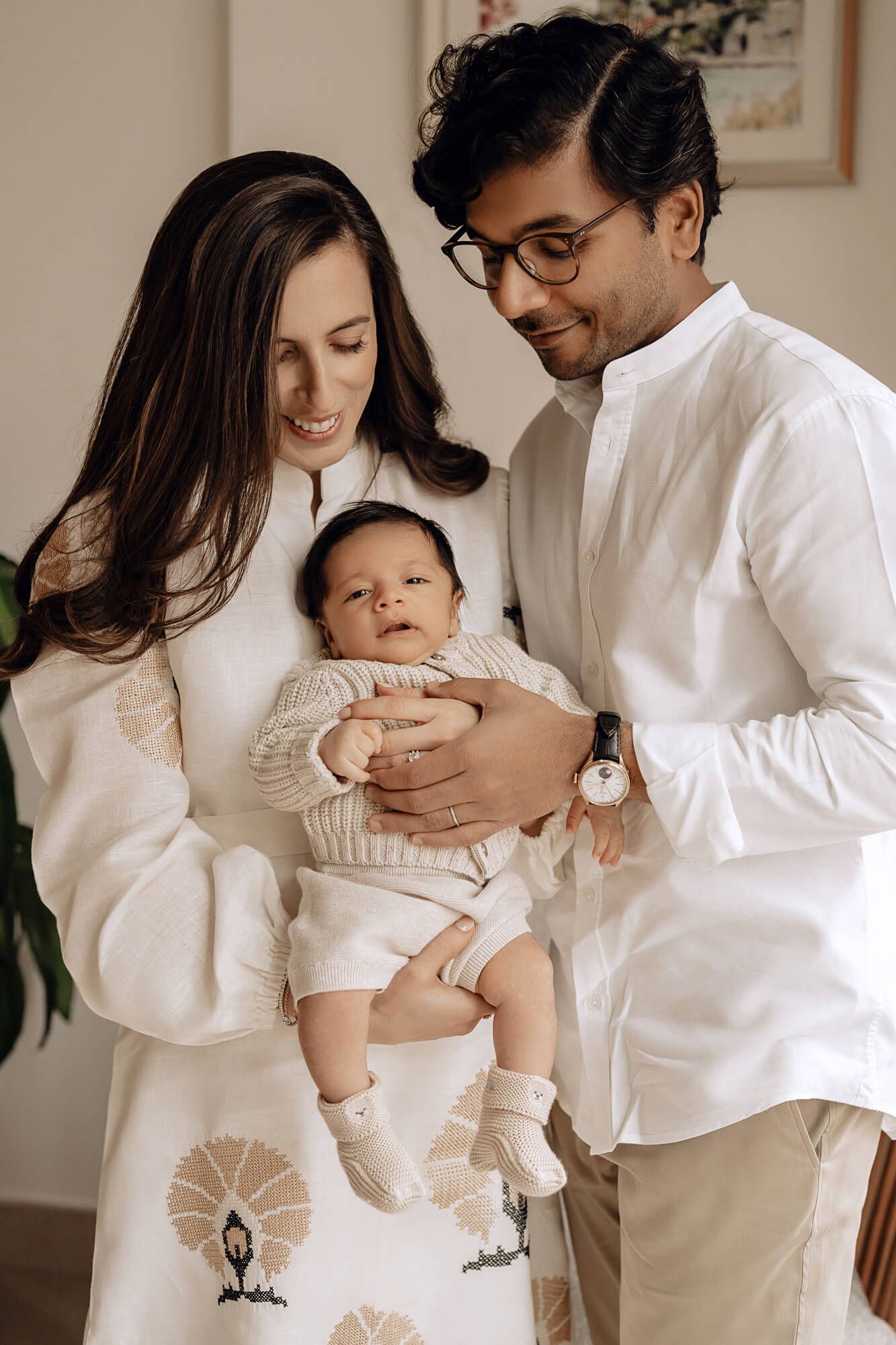 Modern family photoshoot in matching white outfits with their infant.