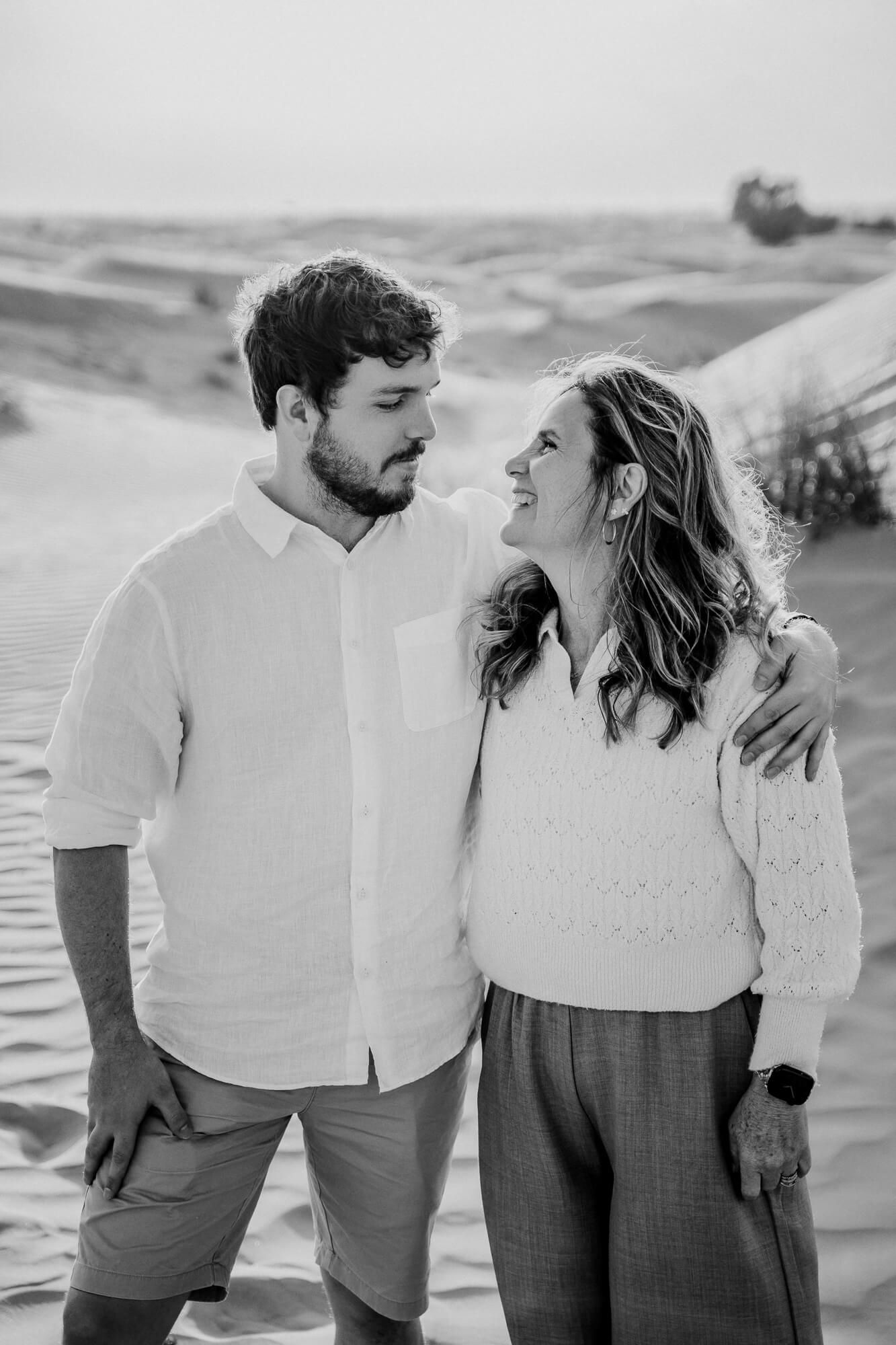 Black and white desert portrait showcasing genuine emotion against rolling sand dunes.