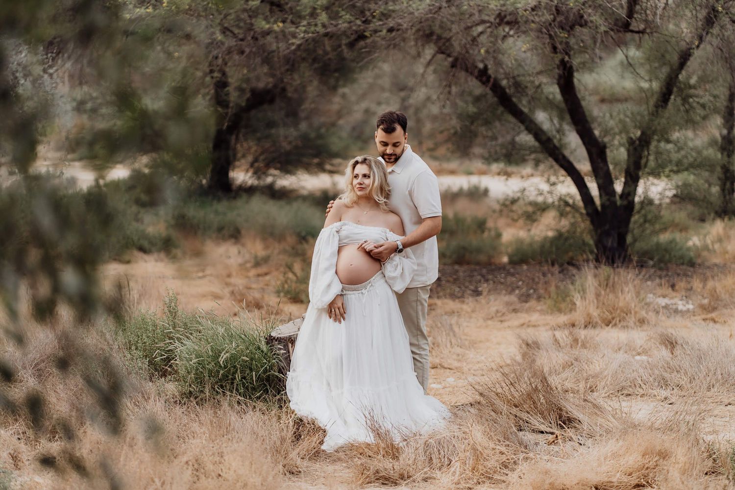 Panoramic maternity photos showing couple's tender moments in desert landscape.