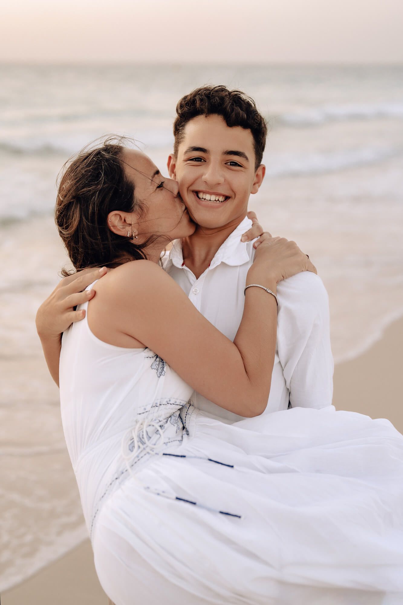 Sweet candid moments captured during a beach photoshoot with two people in white outfits.