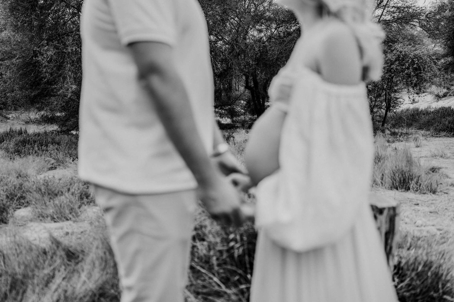 Ethereal maternity photos captured in a sun-drenched field with couple dressed in flowing white.
