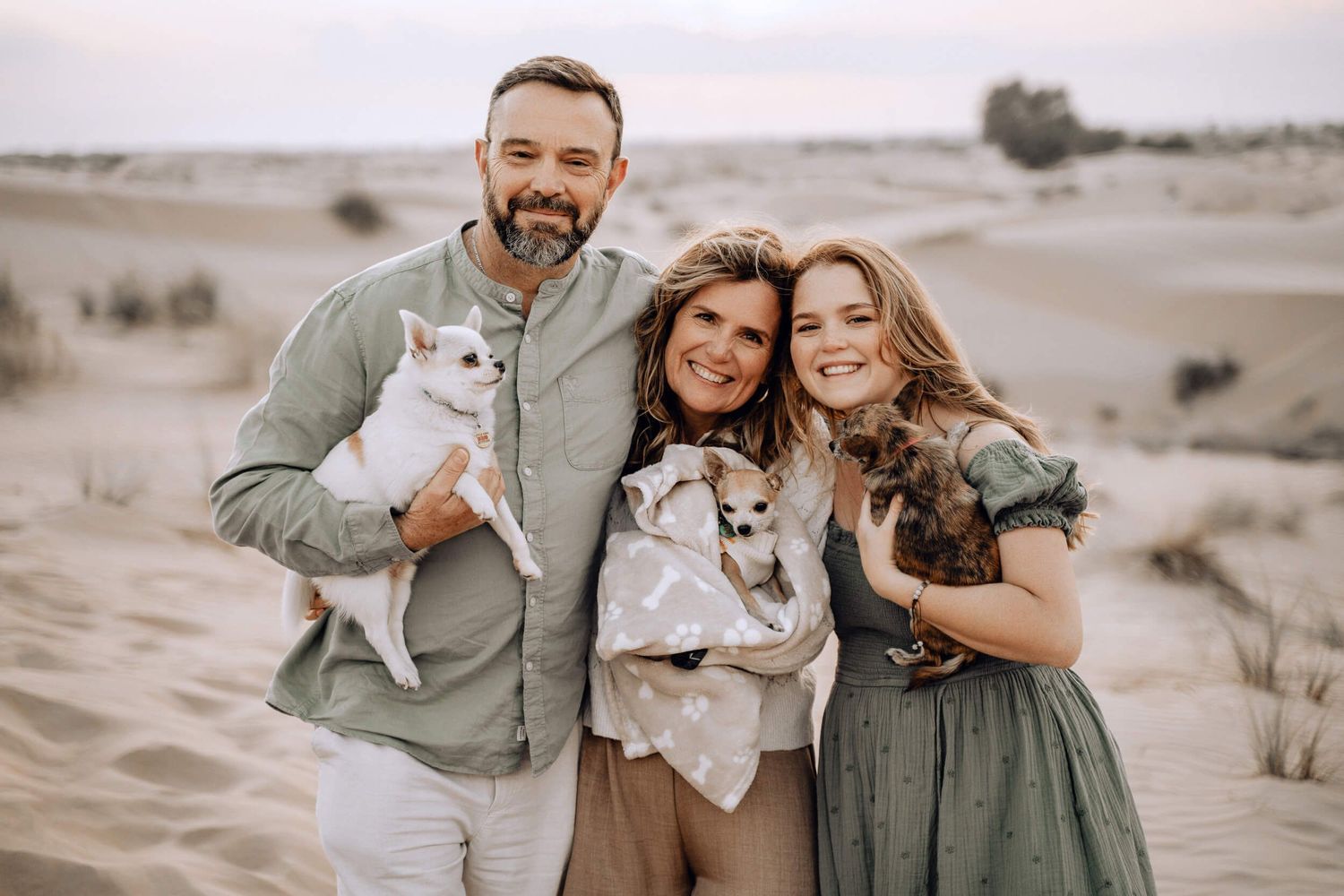 Happy couple with their chihuahua dog enjoying time in desert sand dunes.
