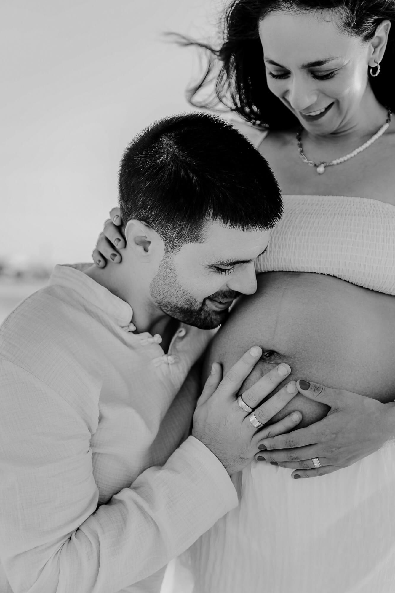 A tender black and white photo series showing intimate moments between expecting partners during a pregnancy photoshoot.