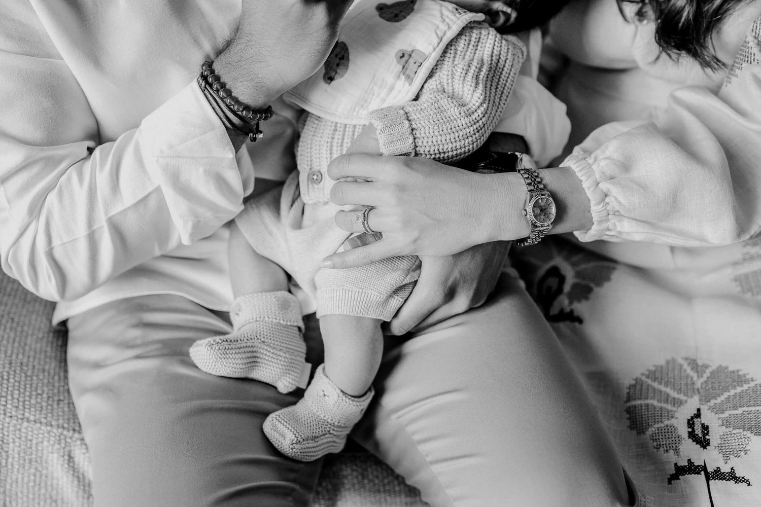Warm family moment showing nurturing interaction with baby in monochromatic setting.