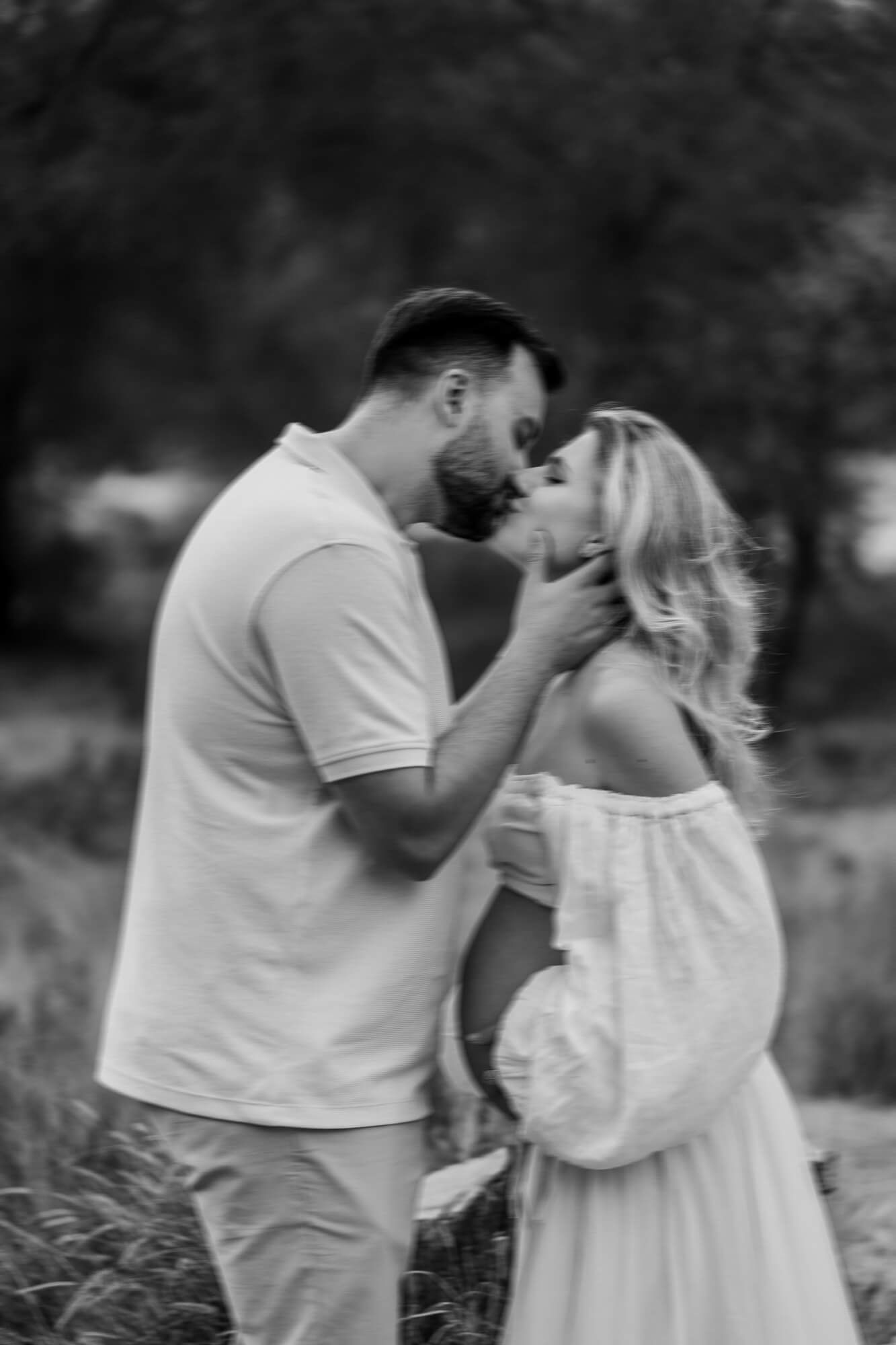Black and white portrait of a loving couple embracing in a natural outdoor setting.
