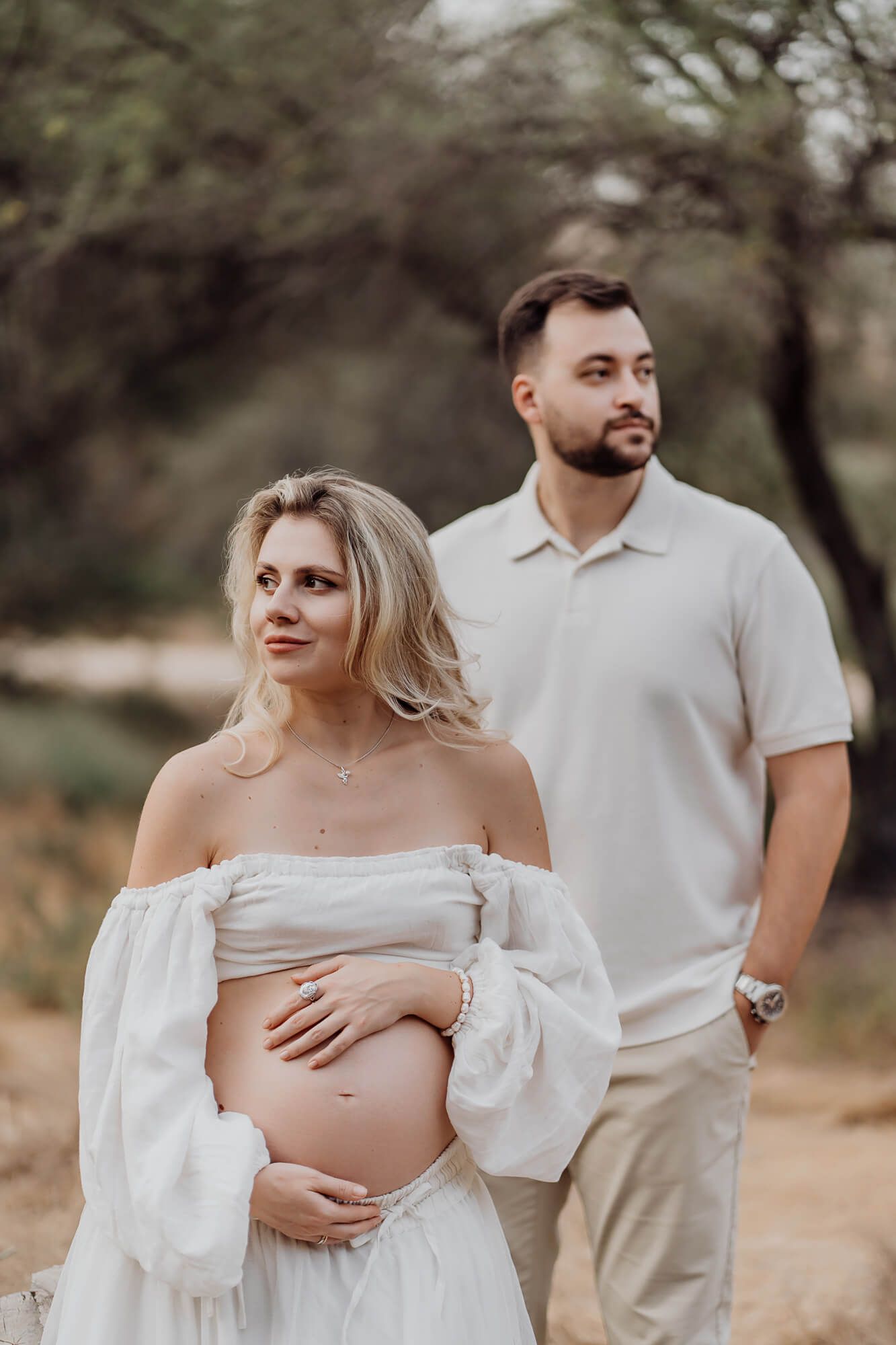 Natural light maternity portraits showcasing couple in coordinated neutral tones.
