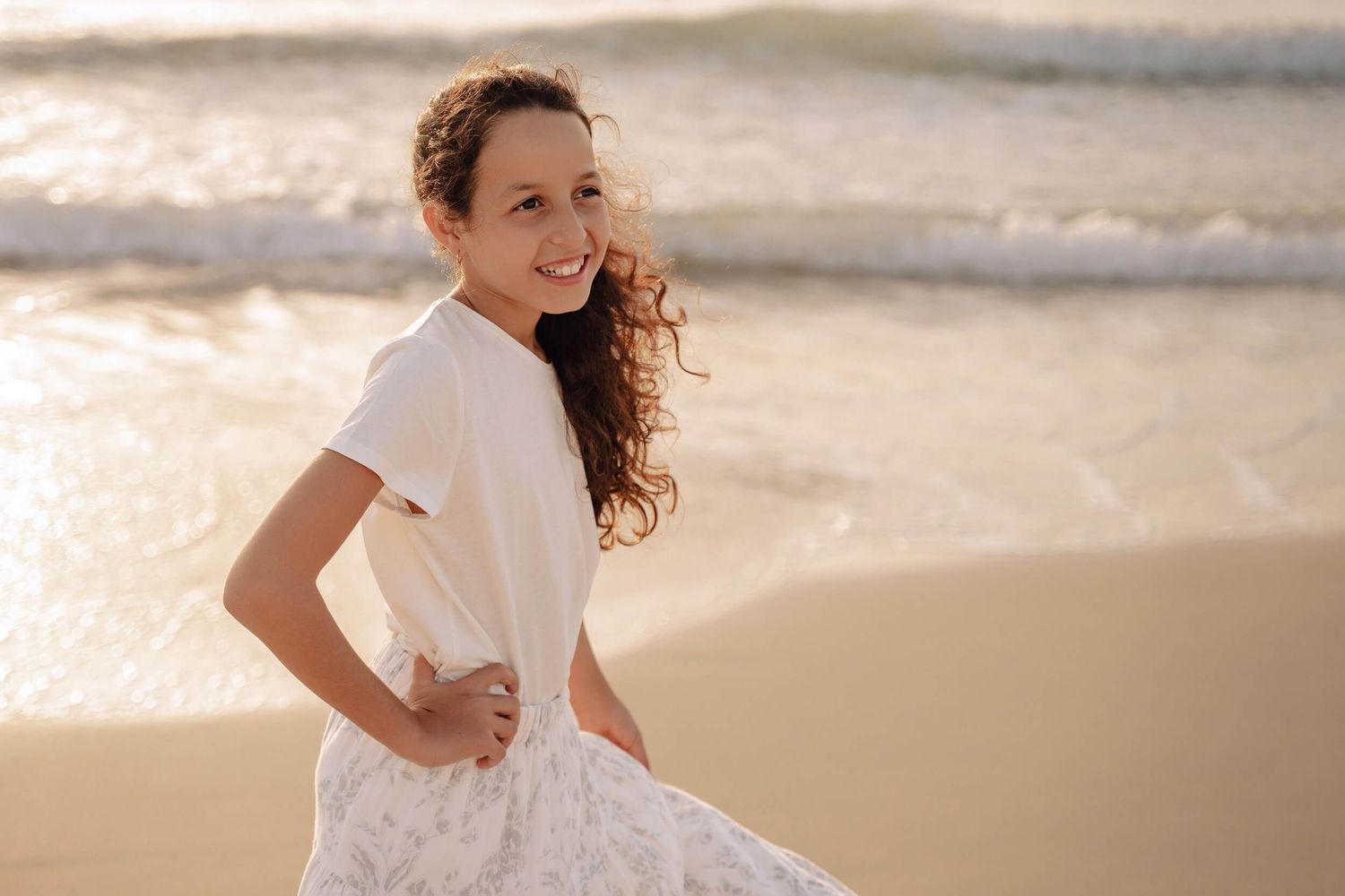 Action shots of a child twirling in a white dress during golden hour at the beach.