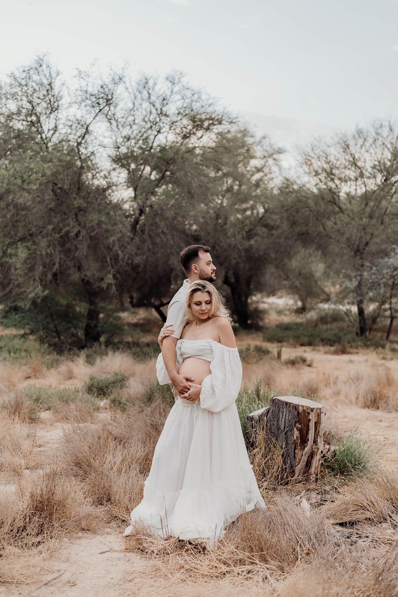 Dreamy maternity photoshoot in rustic outdoor setting with natural earth tones.