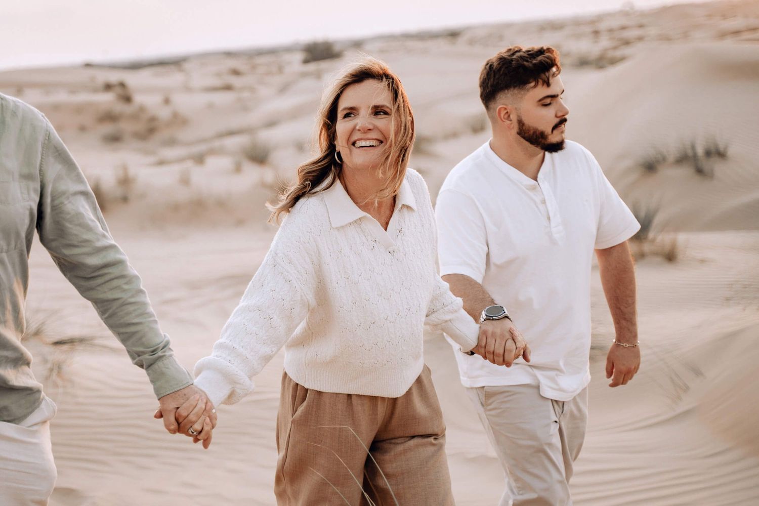Candid moment of joy while walking through desert dunes in casual attire.