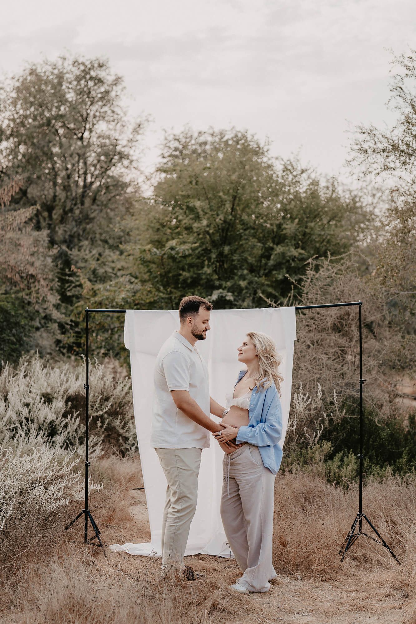Romantic outdoor photoshoot with white backdrop and stands set up in a natural desert setting.