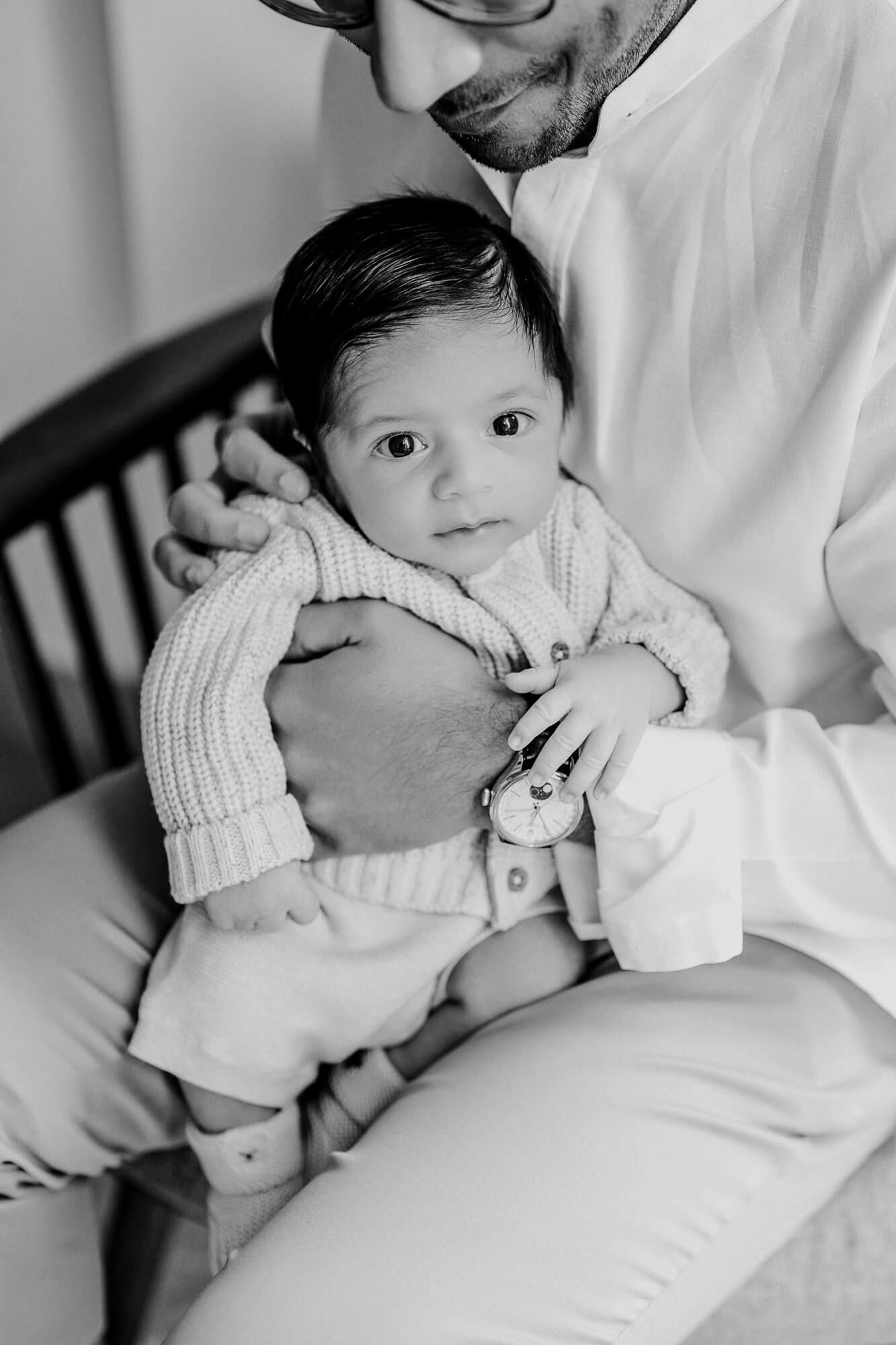 Black and white intimate portrait of parent with baby in knit sweater.