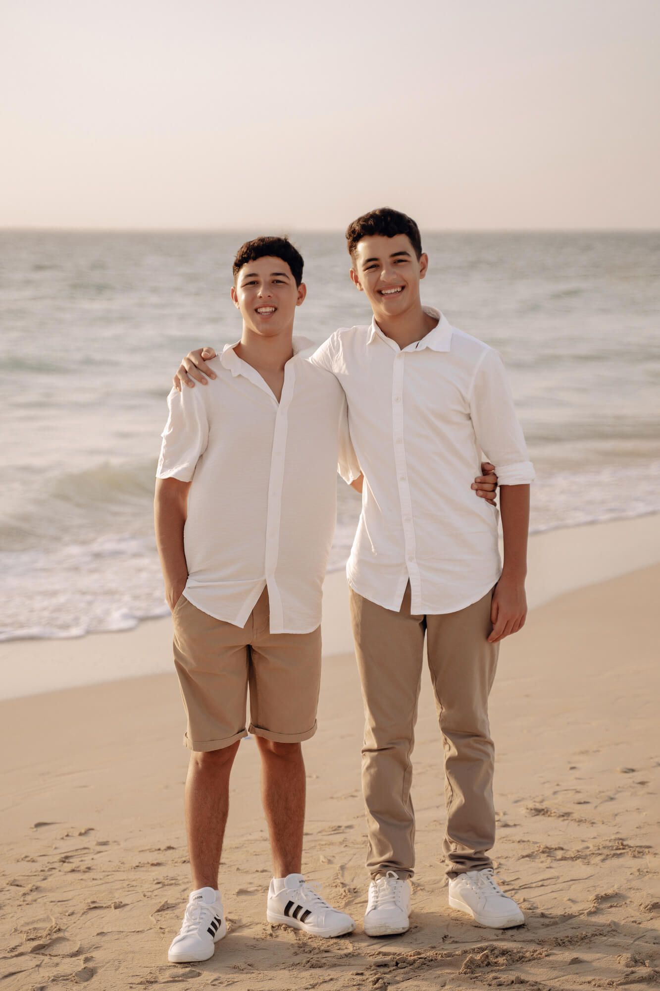 Group photo on beach with matching white shirts and casual poses.