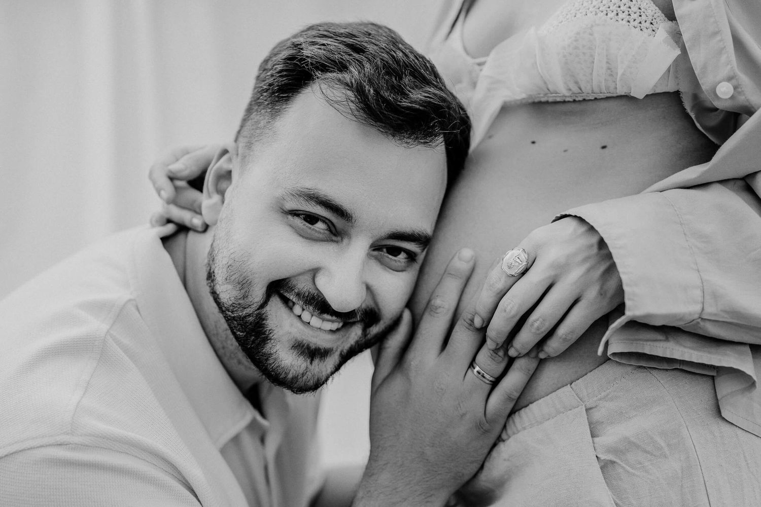 Intimate black and white portrait capturing a tender pregnancy announcement moment.