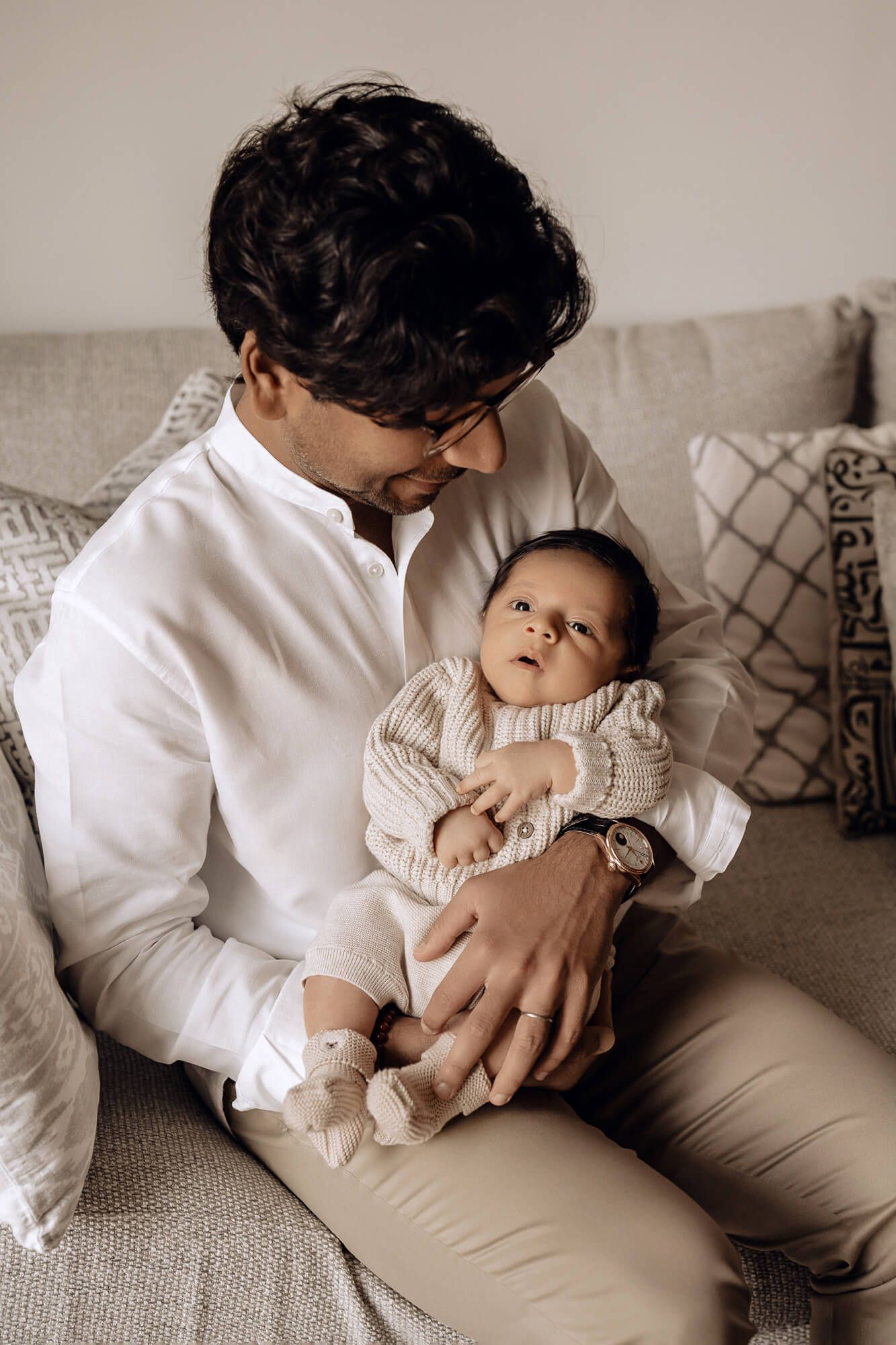 A tender moment captured between parent and baby on a comfortable grey sofa.
