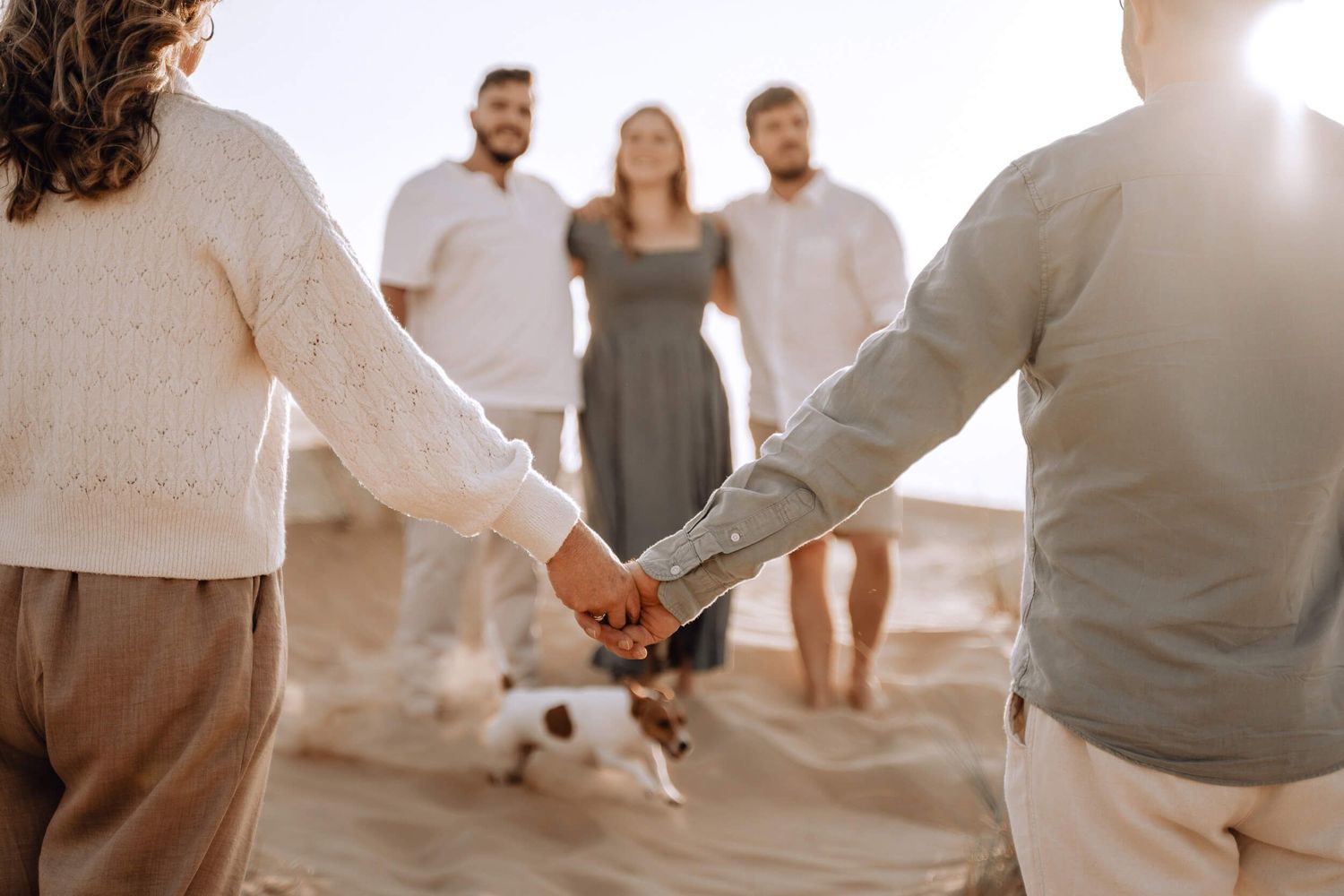 Sun-drenched photos of group gathering on desert dunes wearing coordinated neutral outfits.