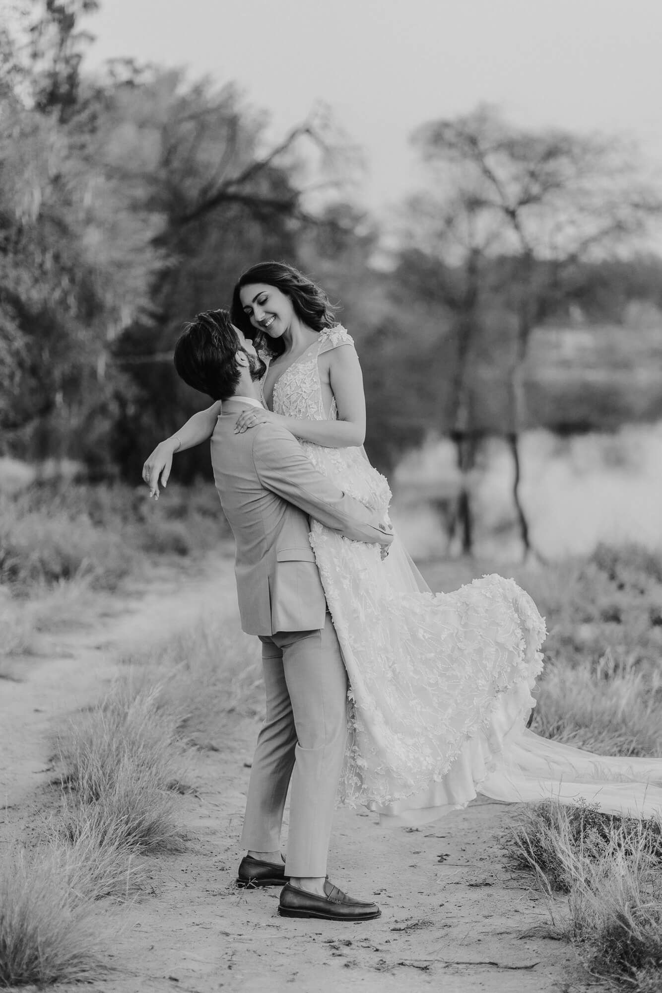 A romantic black and white photo sequence of a couple embracing in a desert landscape with tall grasses.