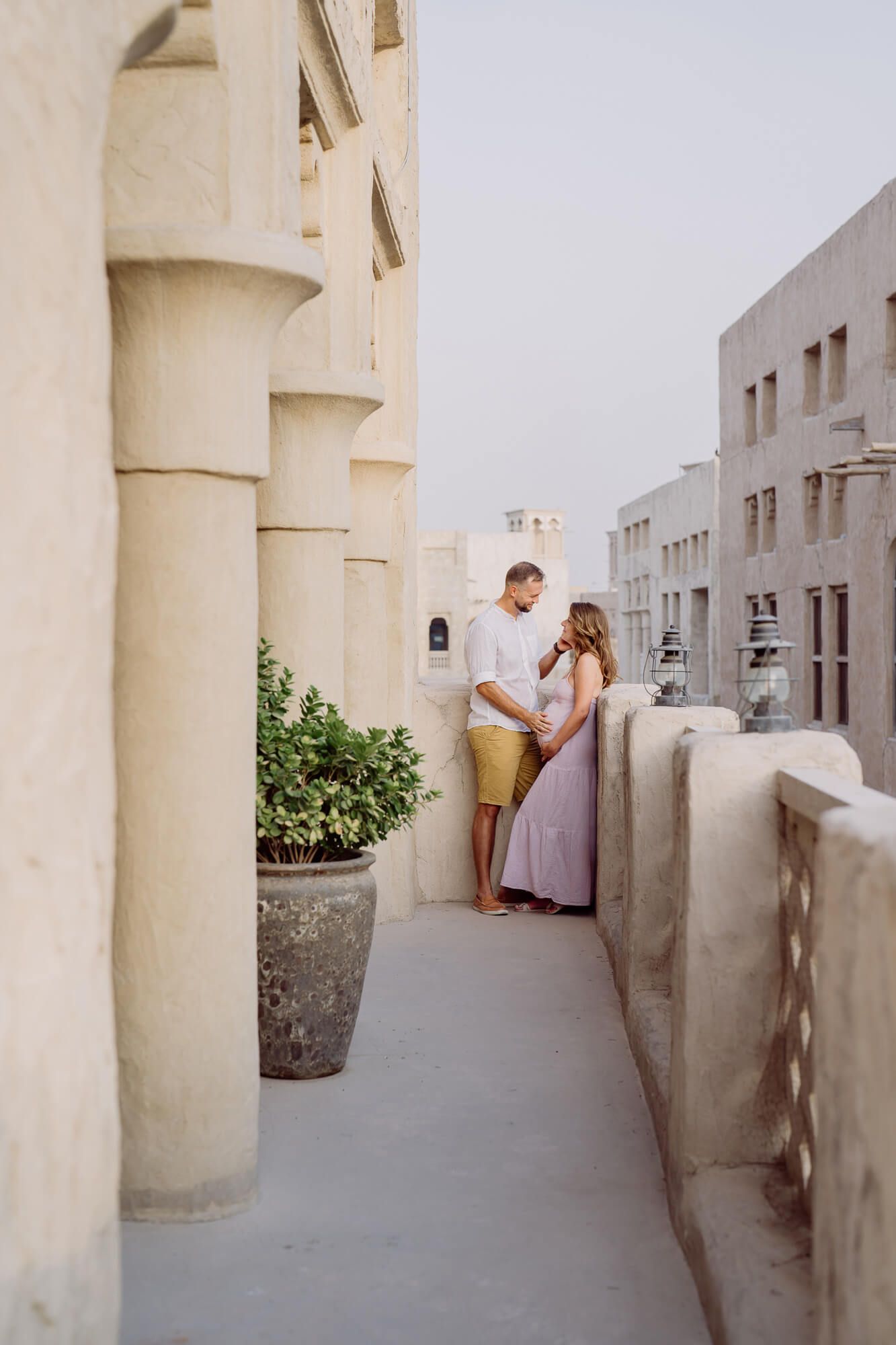 Architectural maternity photo with couple in soft colors against cream columns and walls.
