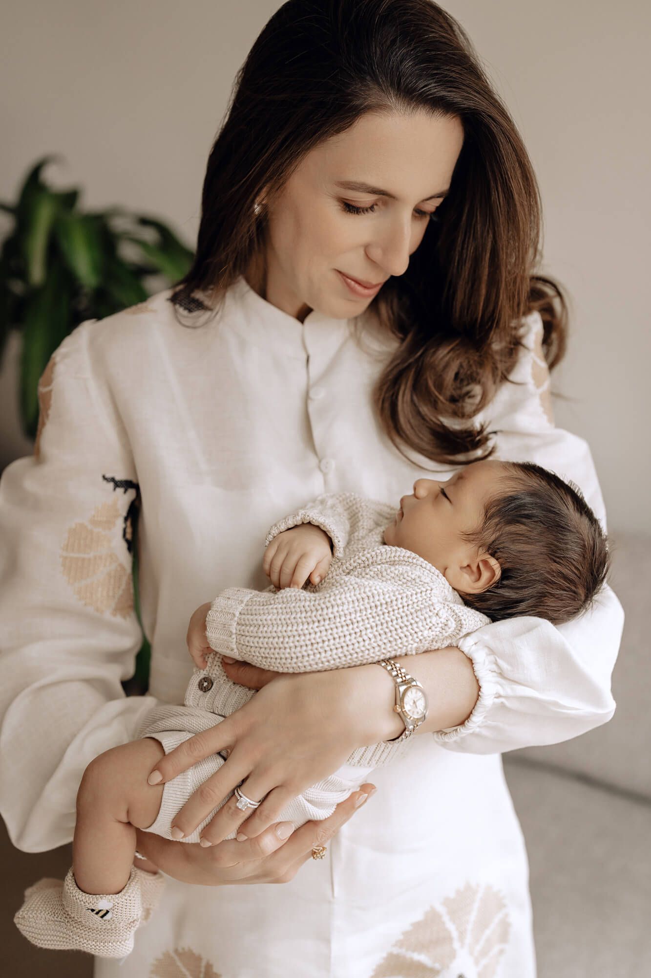 A tender moment of mother and baby cuddling in soft white clothing.