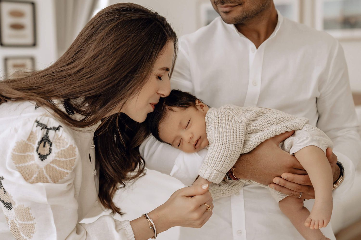 Parents cuddle with their newborn baby in an intimate lifestyle photography session with soft warm lighting.