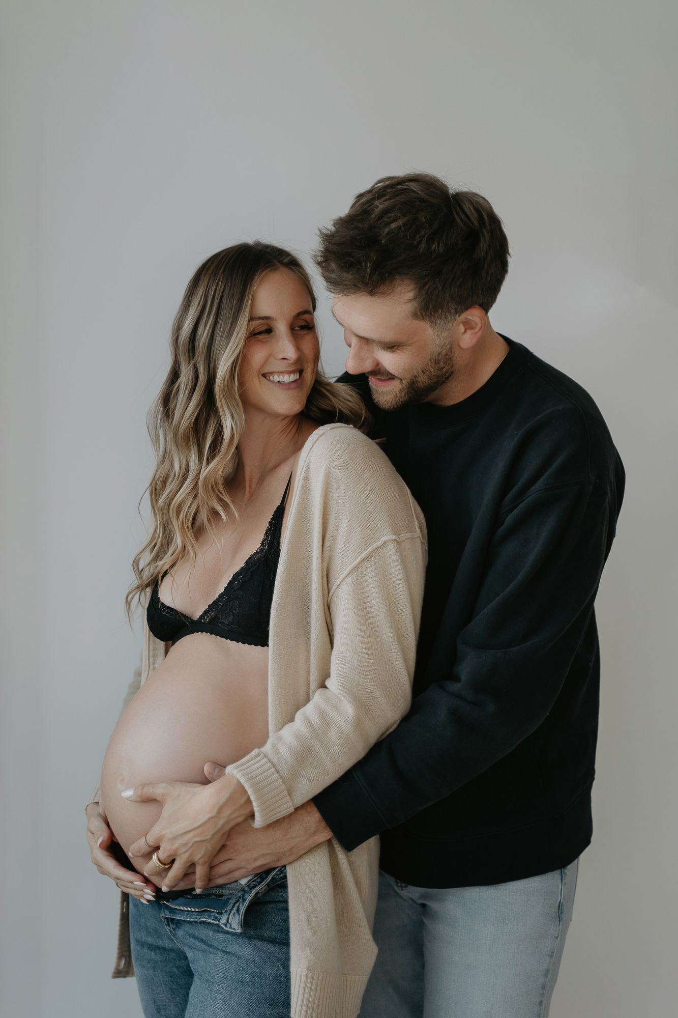 Indoor maternity photos with casual style featuring sweaters and denim.