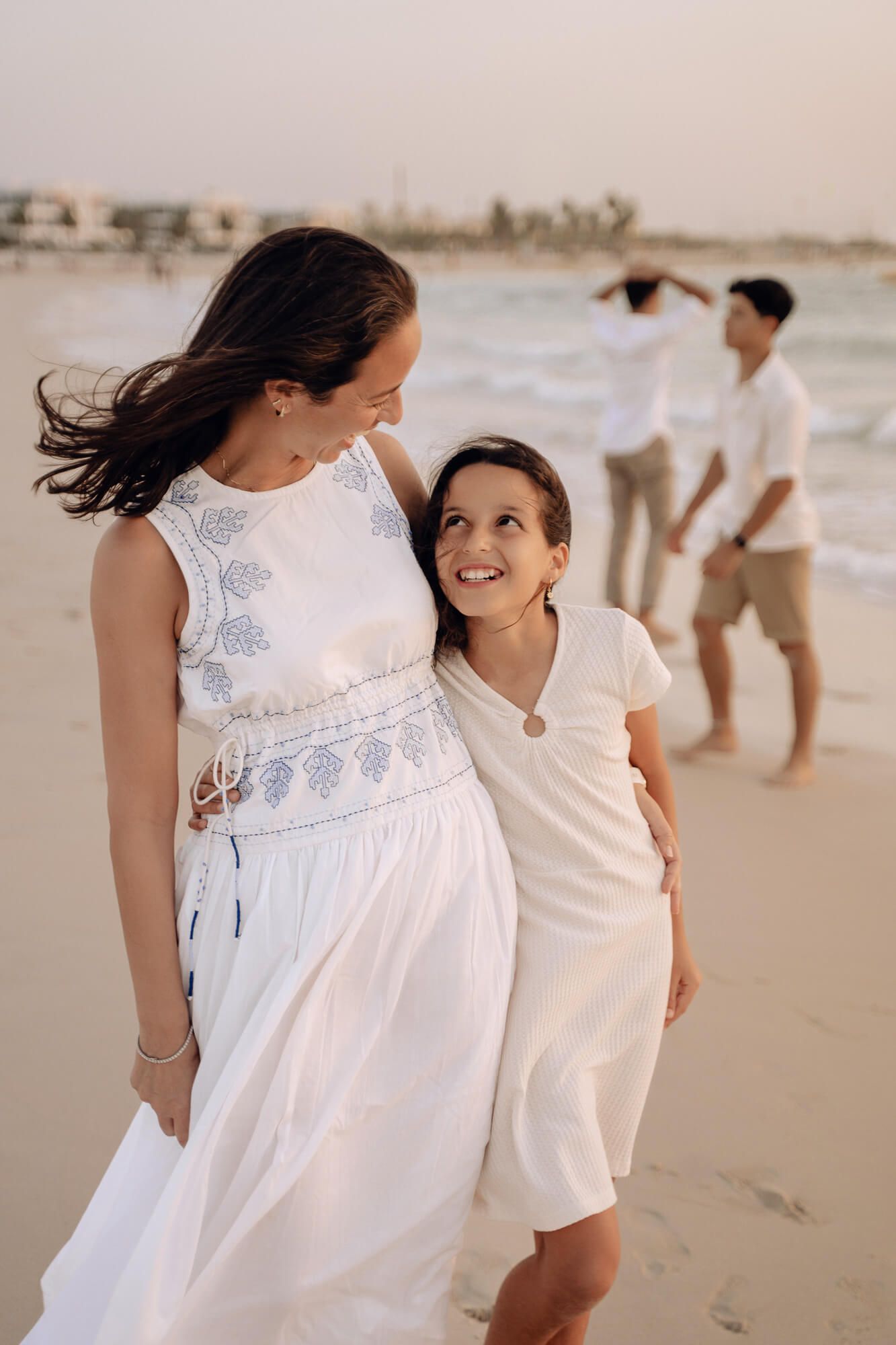 A heartwarming beach scene of people in white outfits walking along the sand at sunset.