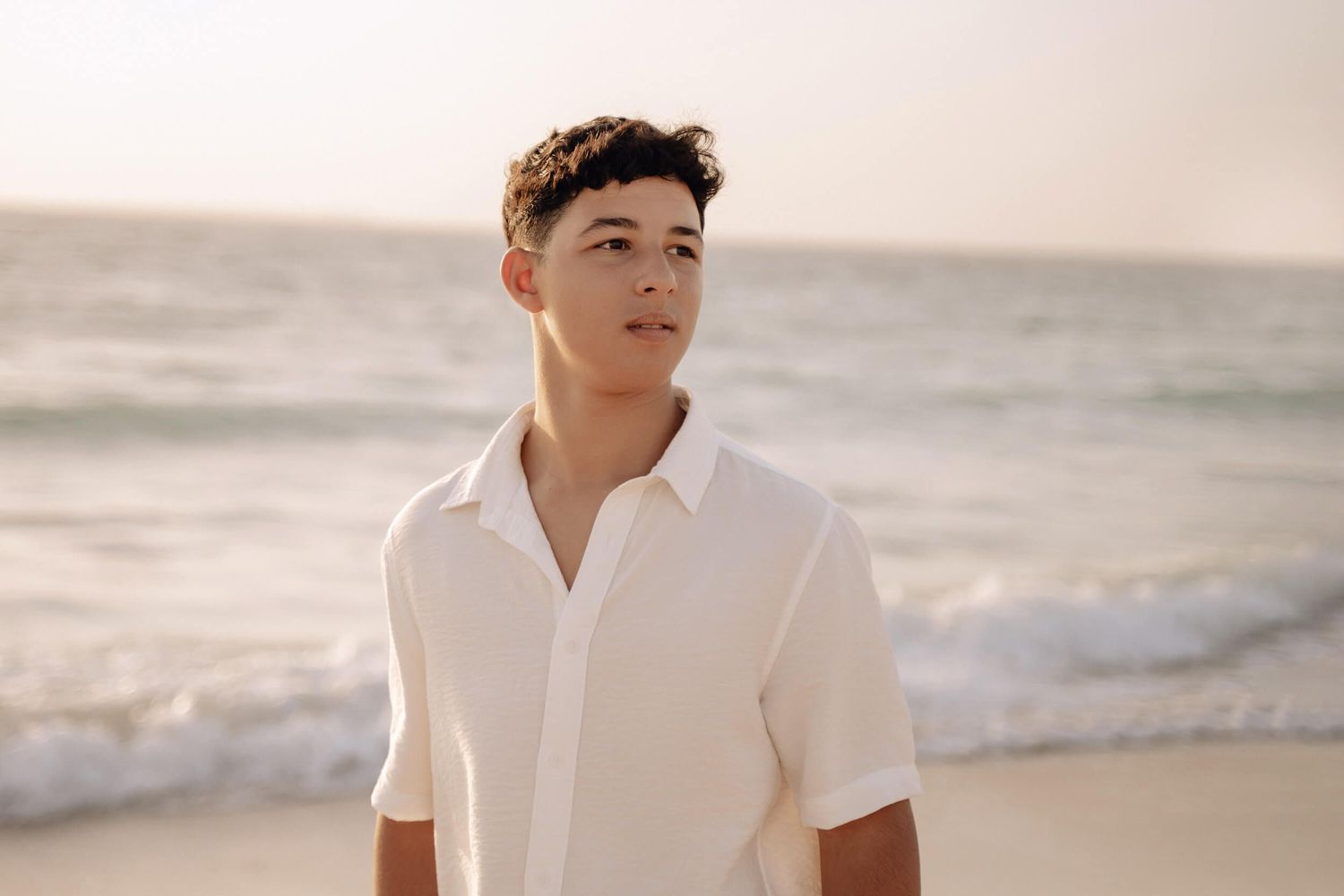 Close up beach portrait of person in white collared shirt during sunset.
