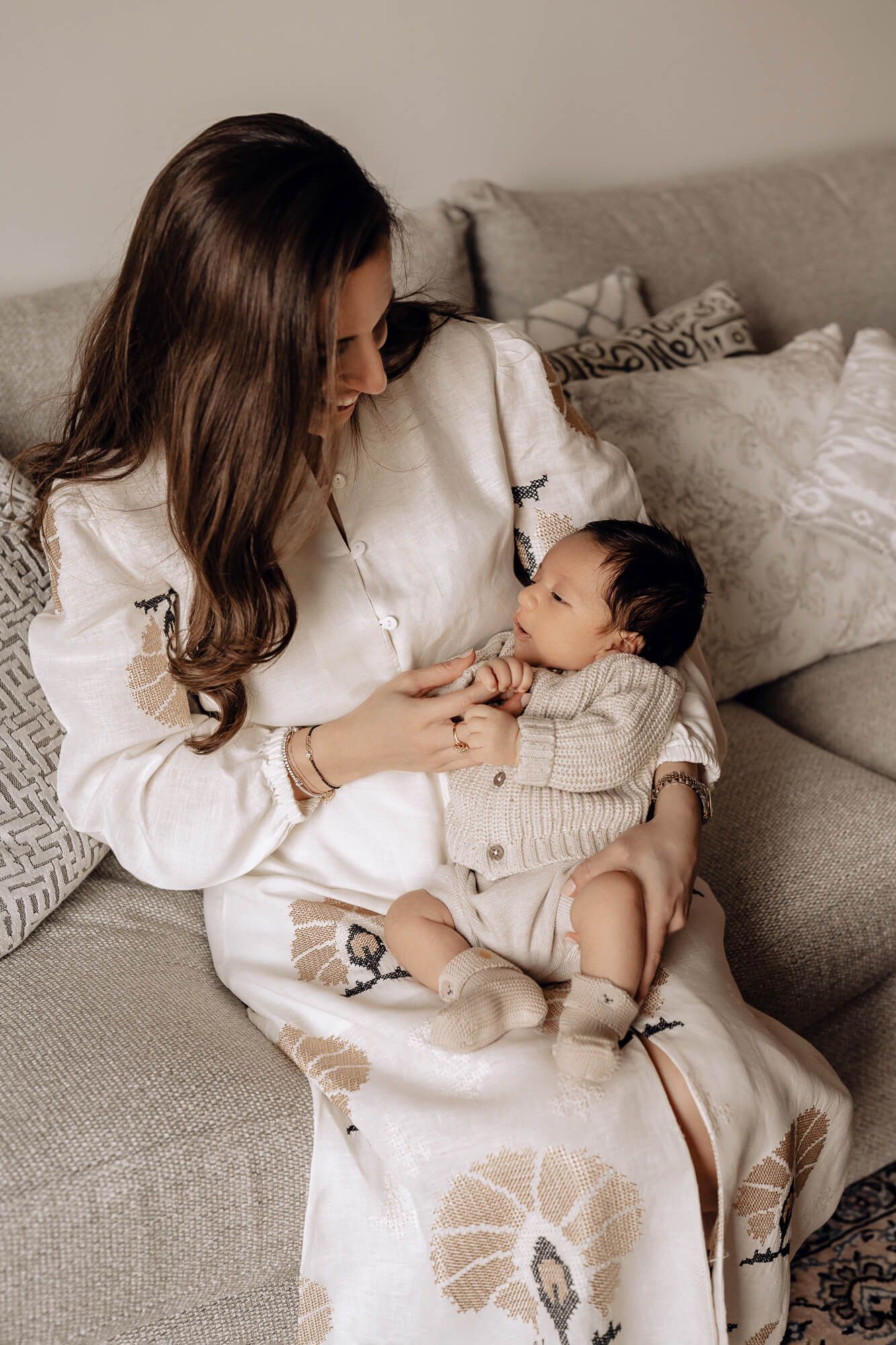 Lifestyle photography series showing quiet moments between parent and baby on grey couch.