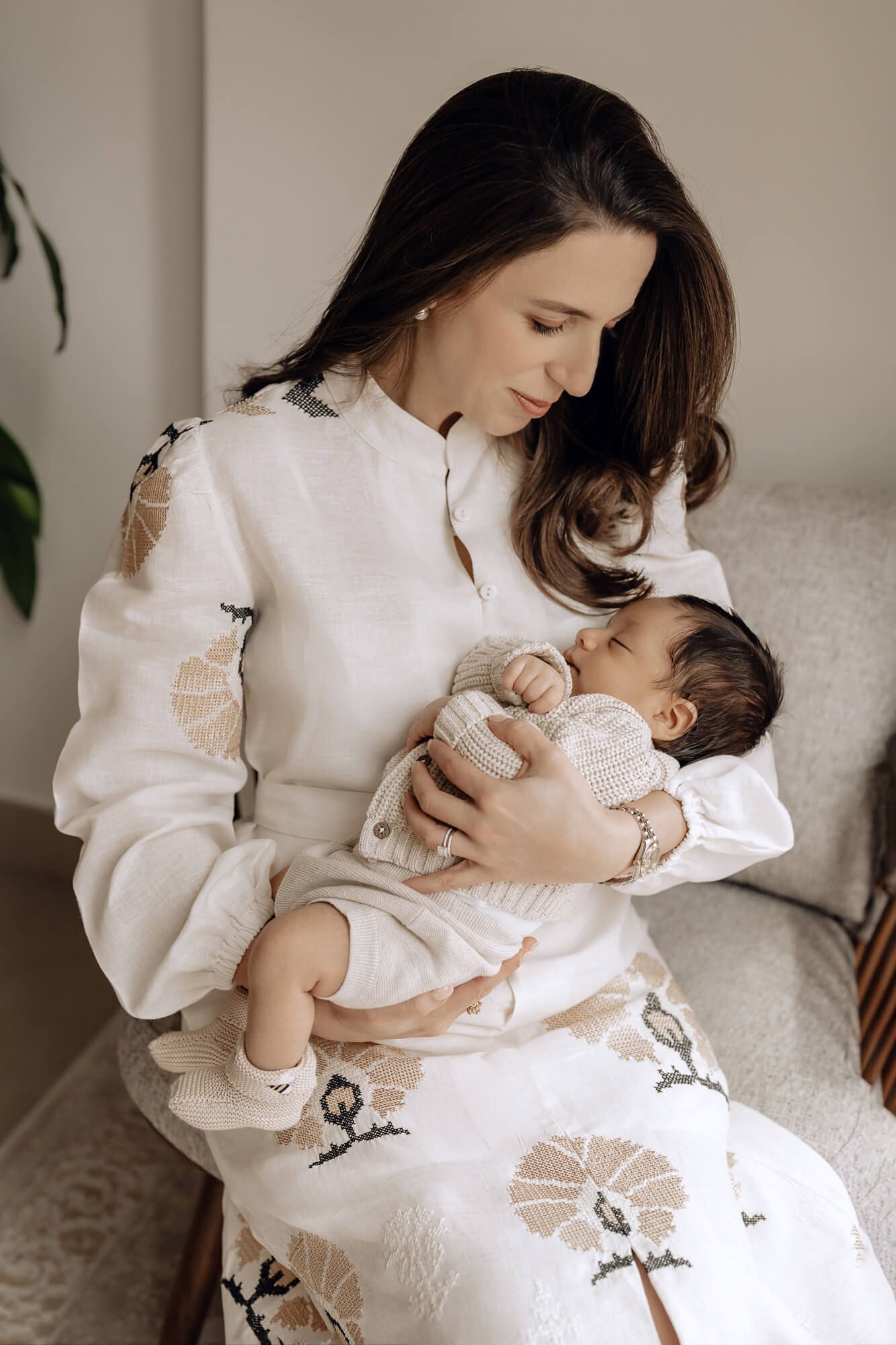 Loving moment between parent and baby in soft white clothing.