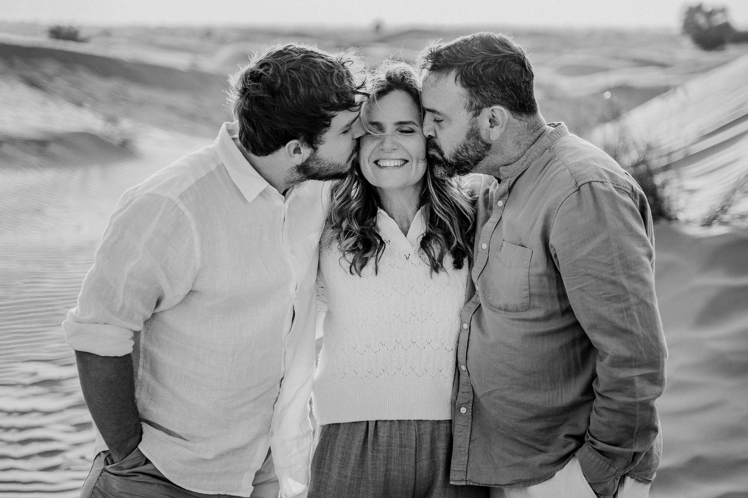 A joyful group embraces each other while posing for photos in a desert landscape setting.