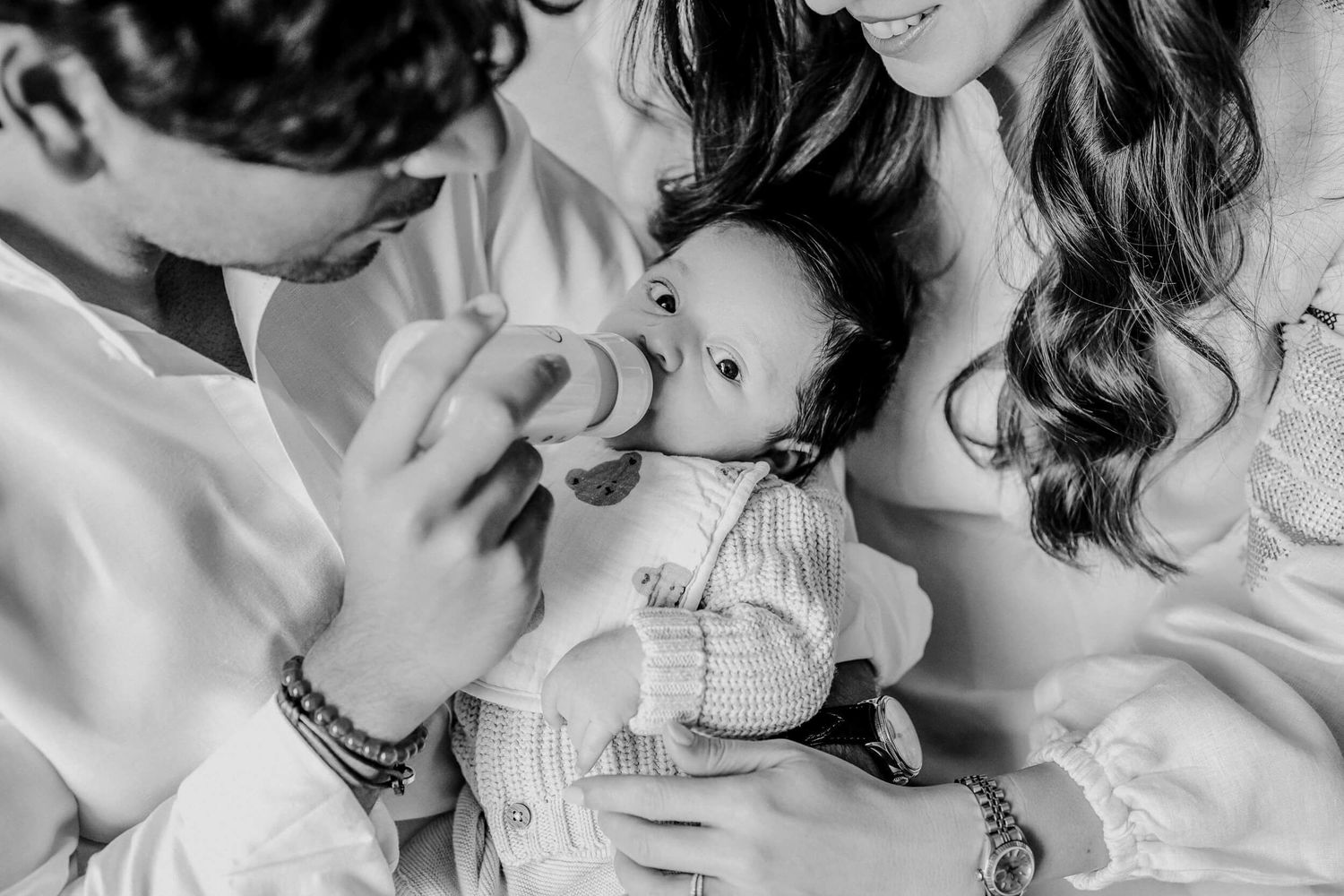 Black and white sequence showing tender family moments with an infant.