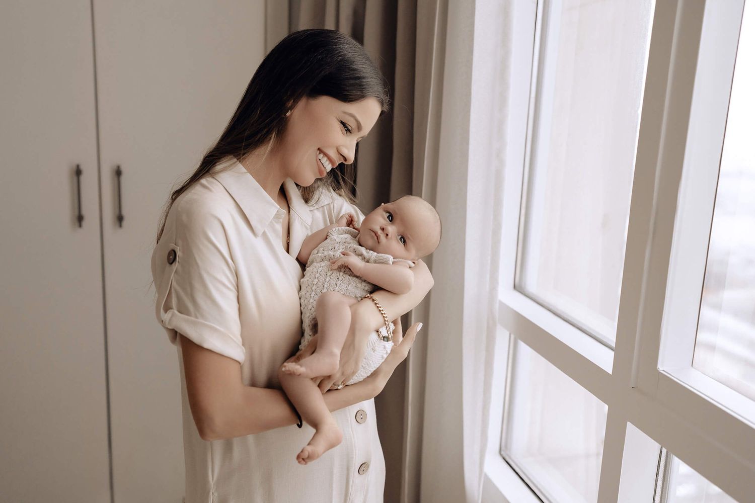 Tender family moment captured in soft light by window.