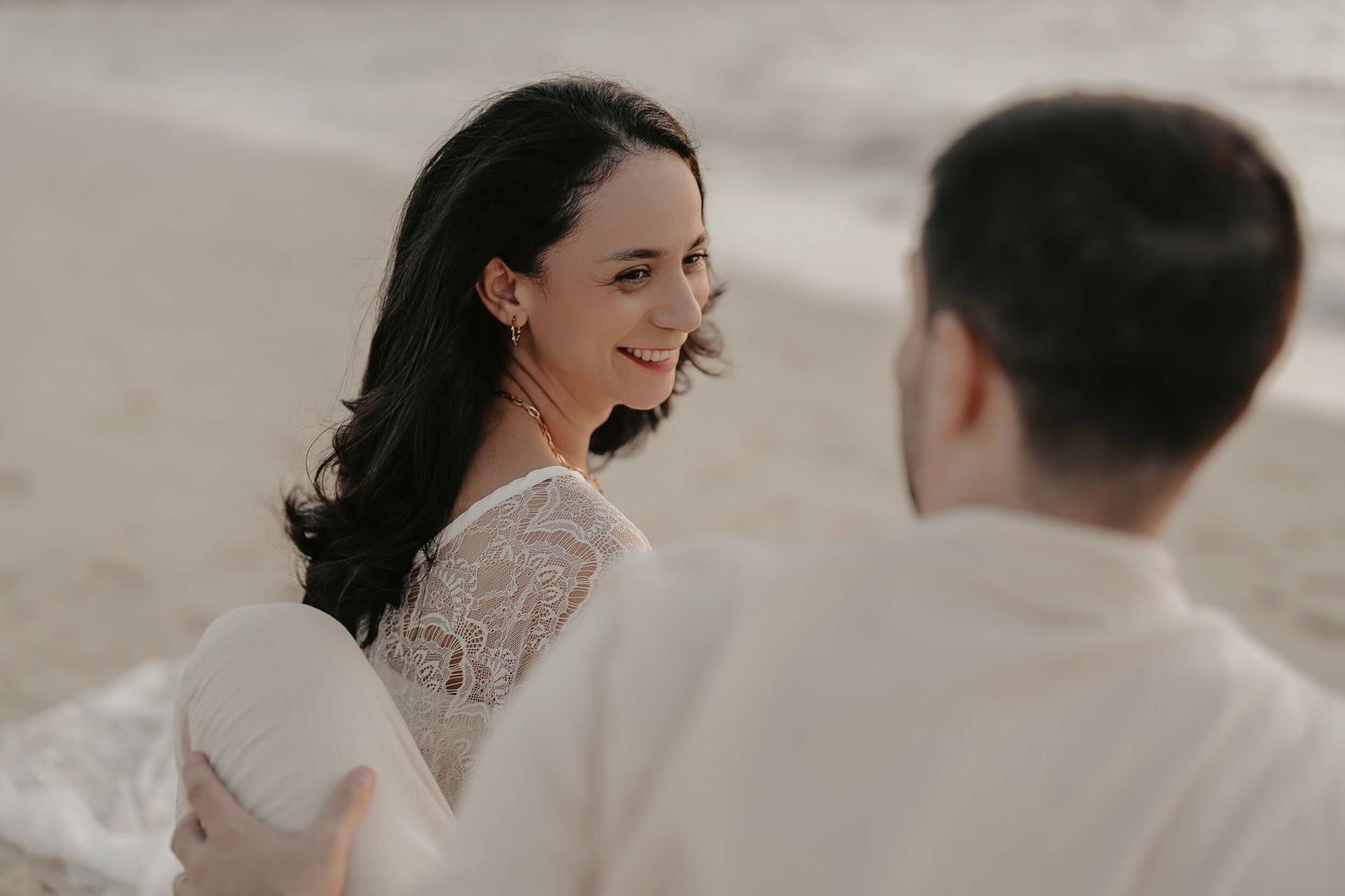 Romantic beachside wedding moment captured in soft muted tones with delicate lace details.
