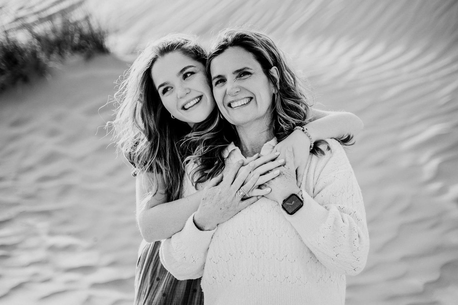 Two people share joyful moment and embrace while standing in desert setting.