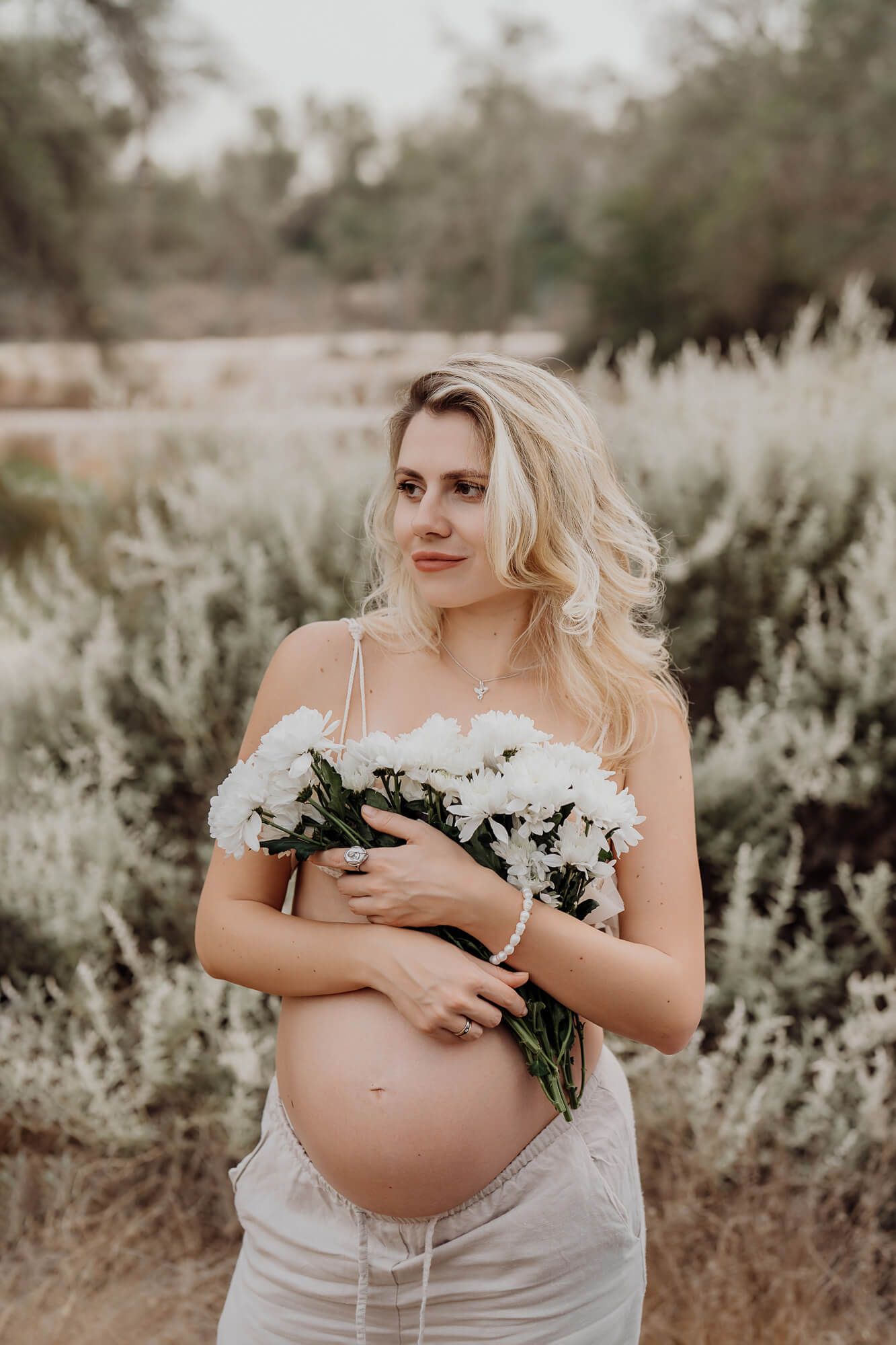 Maternity photography with white daisies against sage brush backdrop.
