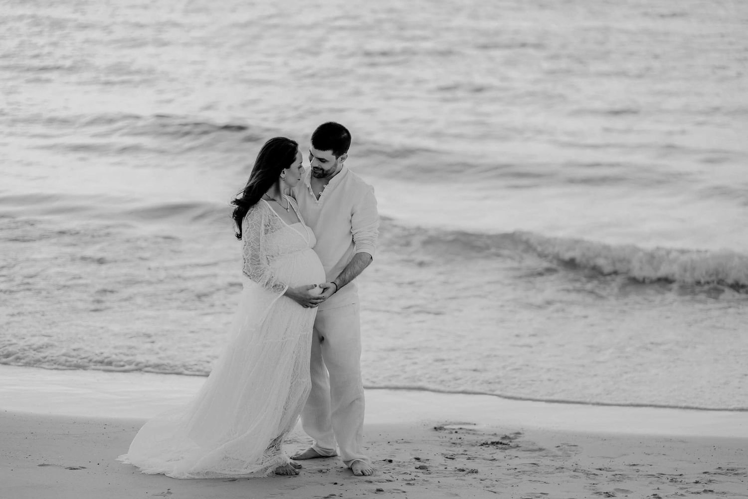 A romantic black and white beach photoshoot showing intimate moments between a couple on their wedding day.
