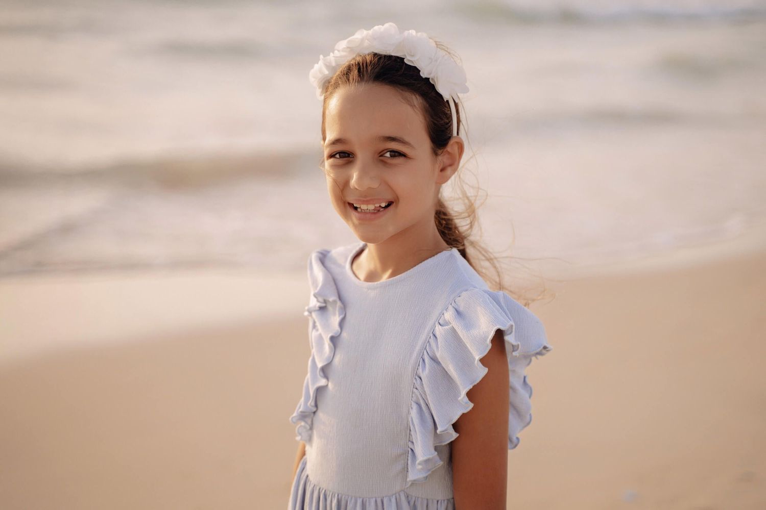 Candid beach portraits featuring a light blue dress against warm sunset tones.