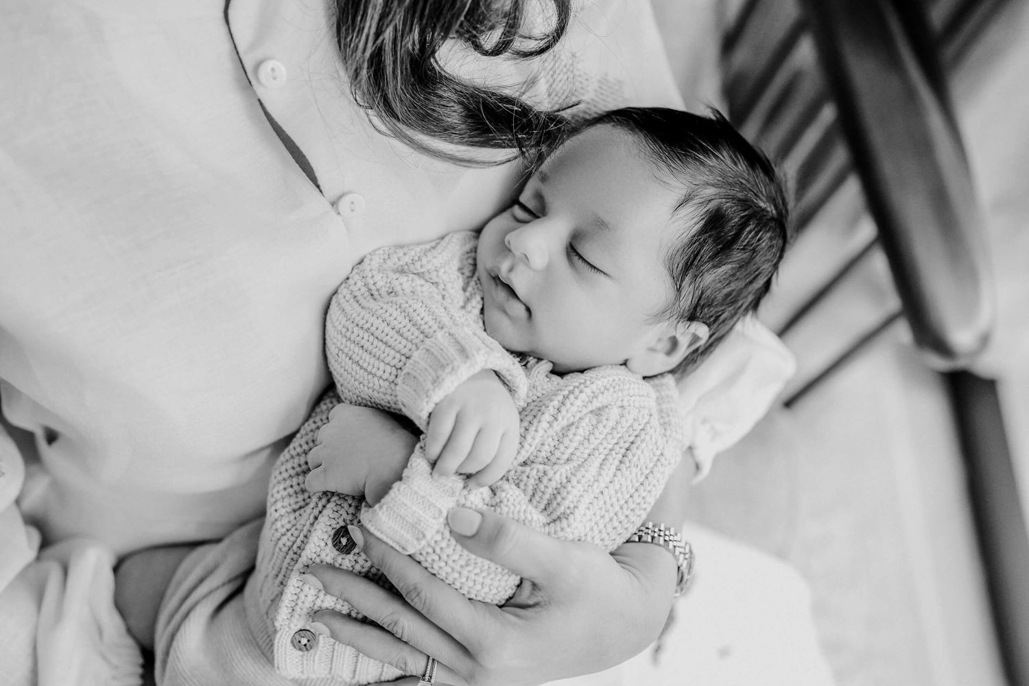Black and white close-up of parent and baby sharing an intimate moment.