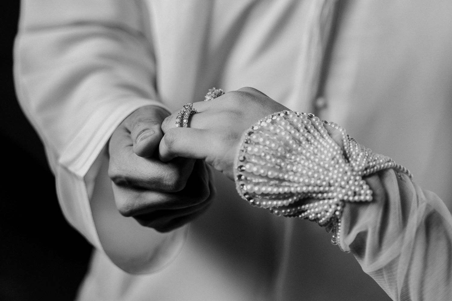 Close-up black and white image of hands holding an ornate beaded hair accessory or brooch.