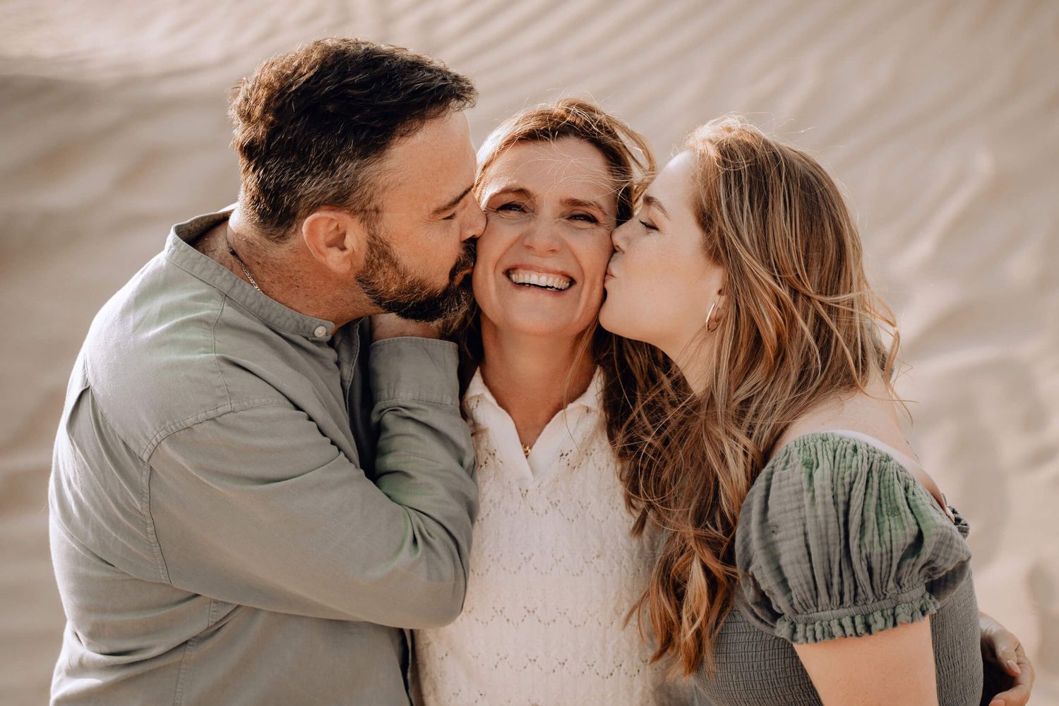 Dad, mother and daughter share an intimate moment embracing and laughing together at the beach.